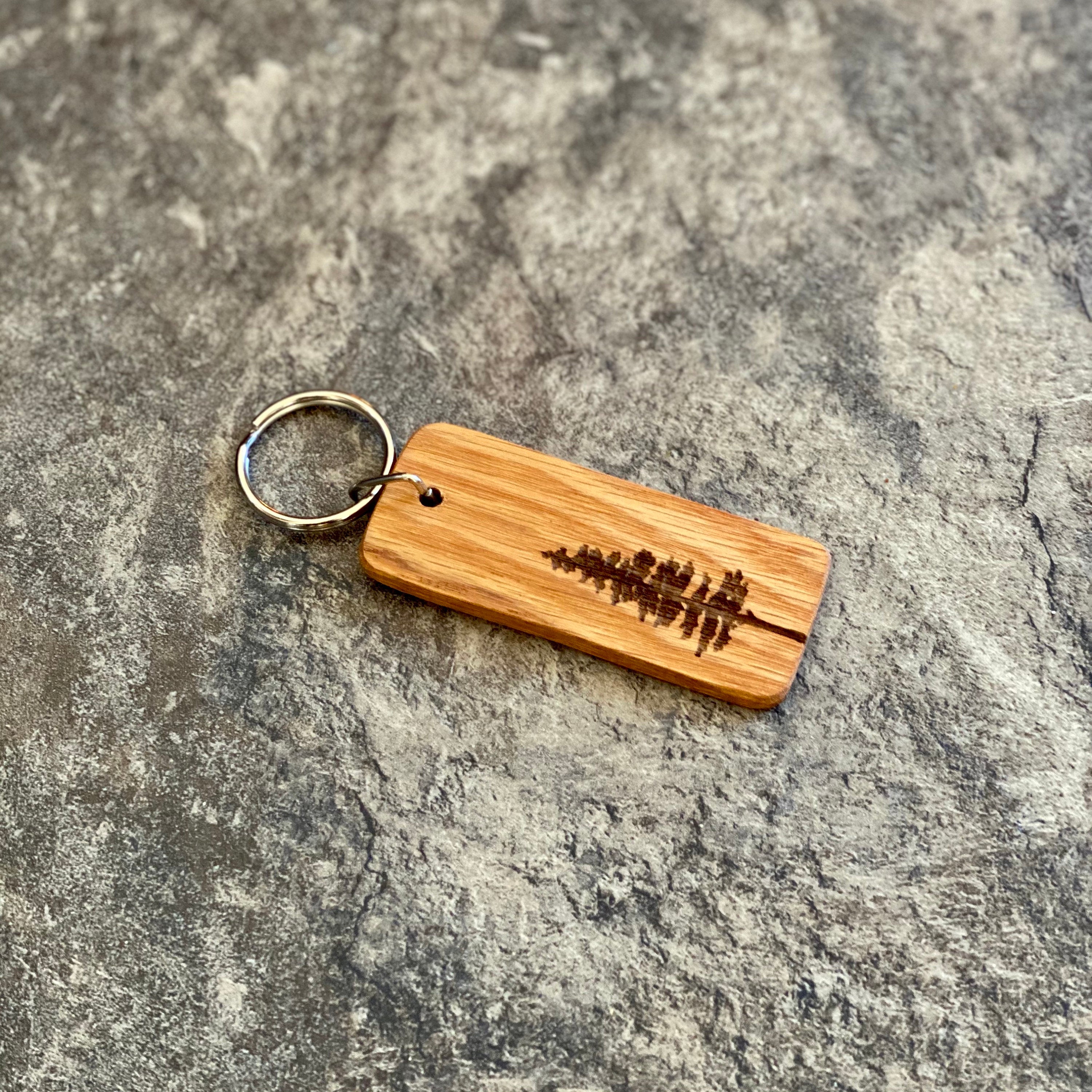 A rustic Pine Tree Engraved Wood Keychain made from solid hardwood oak, featuring a detailed pine tree silhouette and space for personalized text.