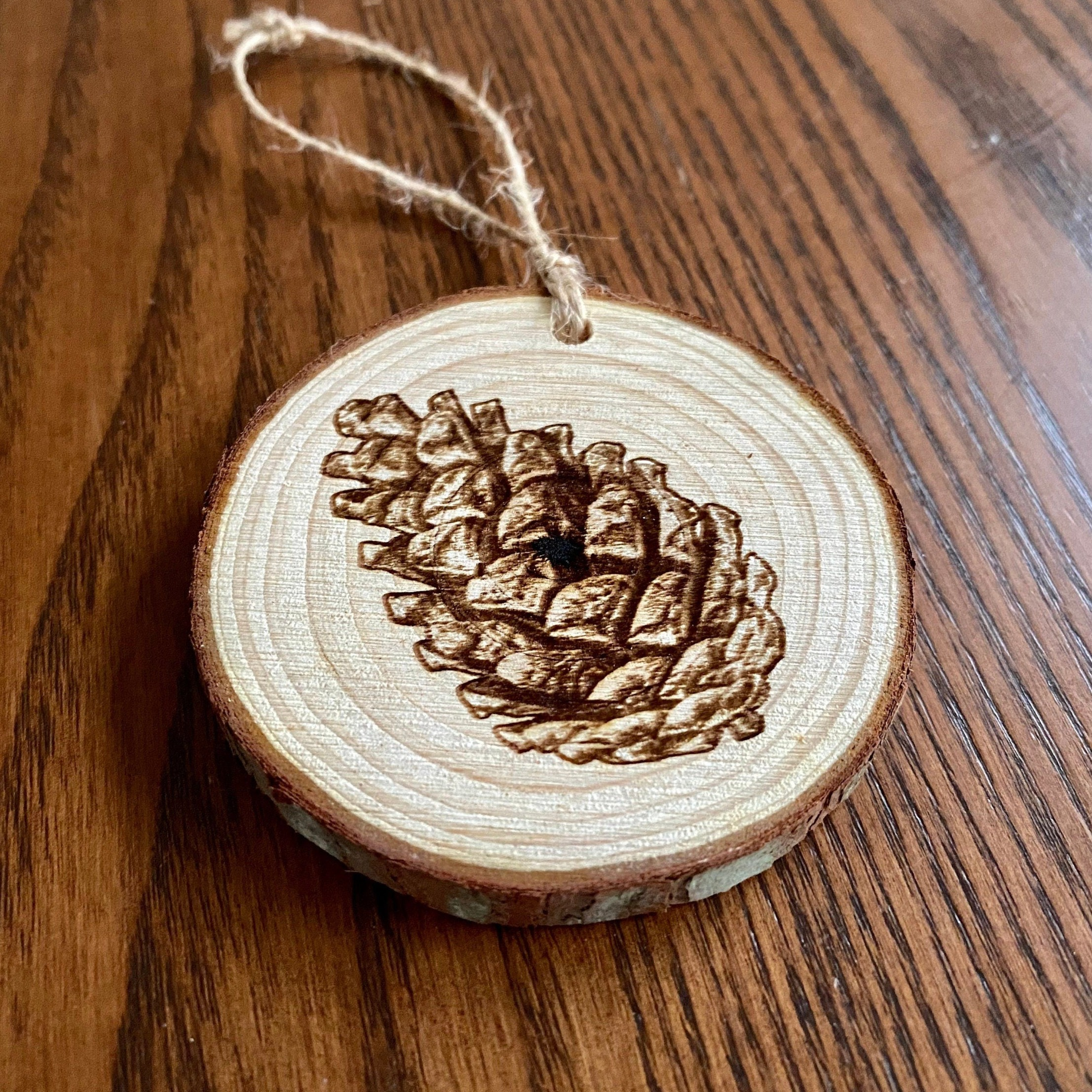 Rustic pinecone engraved wood Christmas ornament with twine, perfect for nature lovers and personalized gifting.