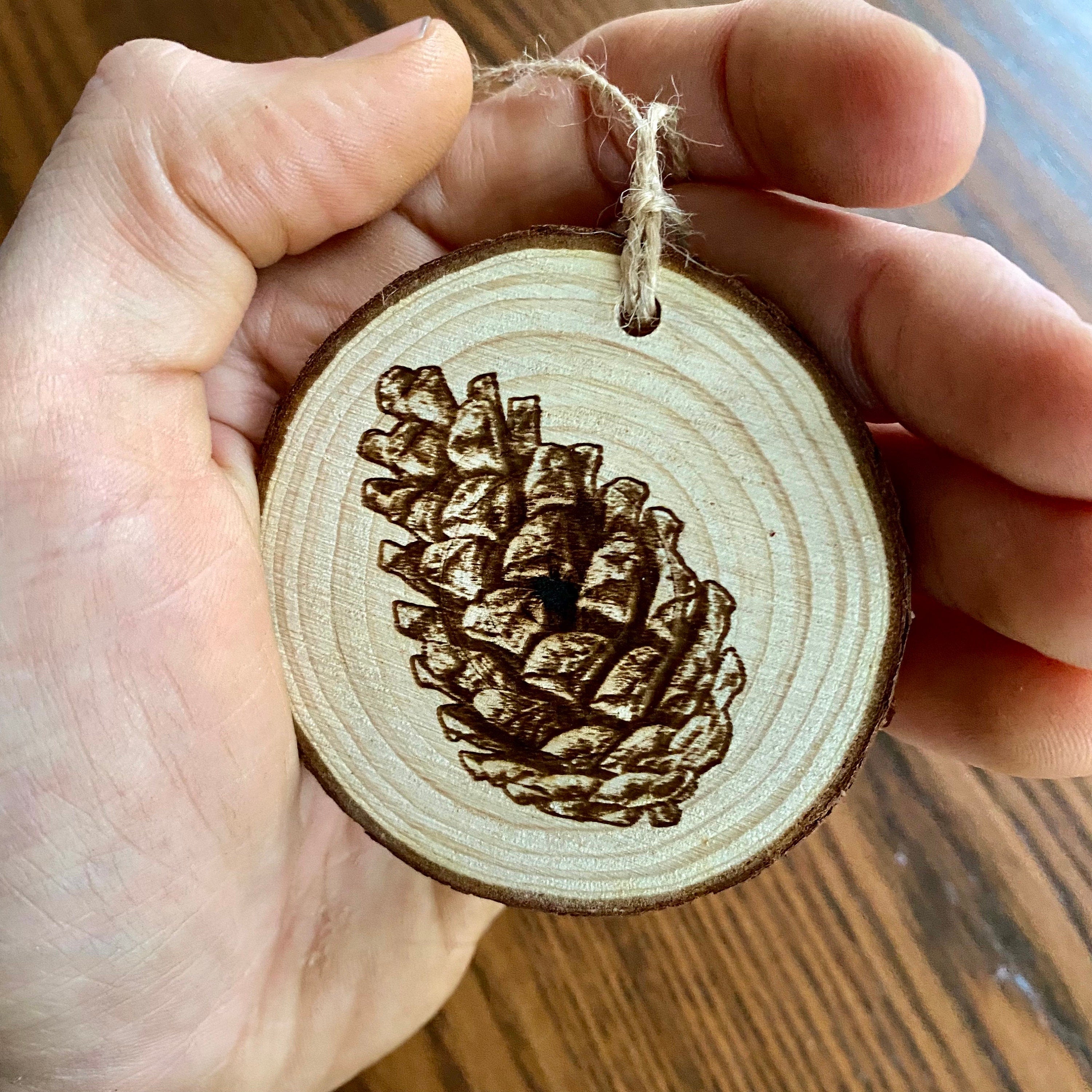 Rustic pinecone engraved wood Christmas ornament with twine, perfect for nature lovers and personalized gifting.