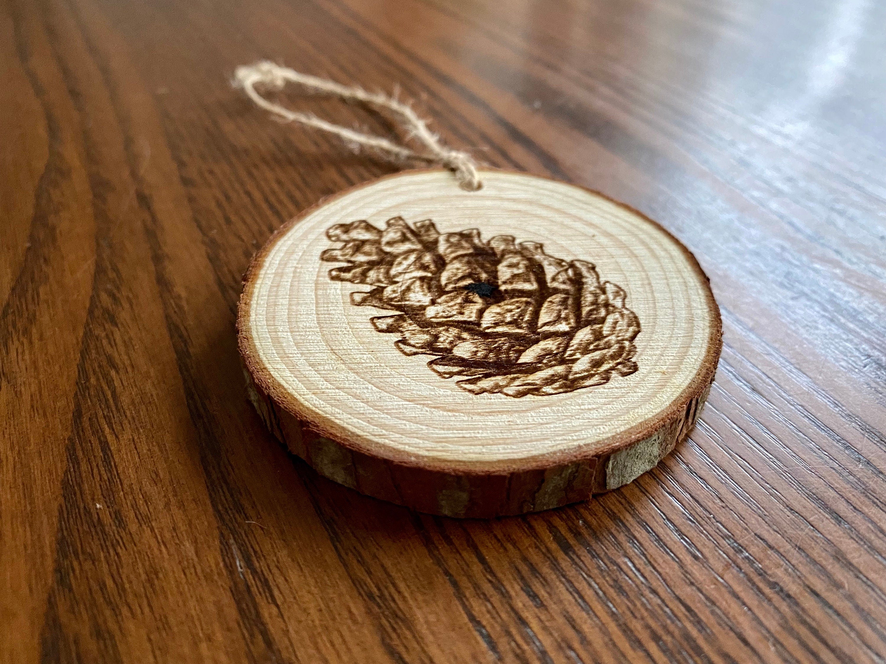 Rustic pinecone engraved wood Christmas ornament with twine, perfect for nature lovers and personalized gifting.