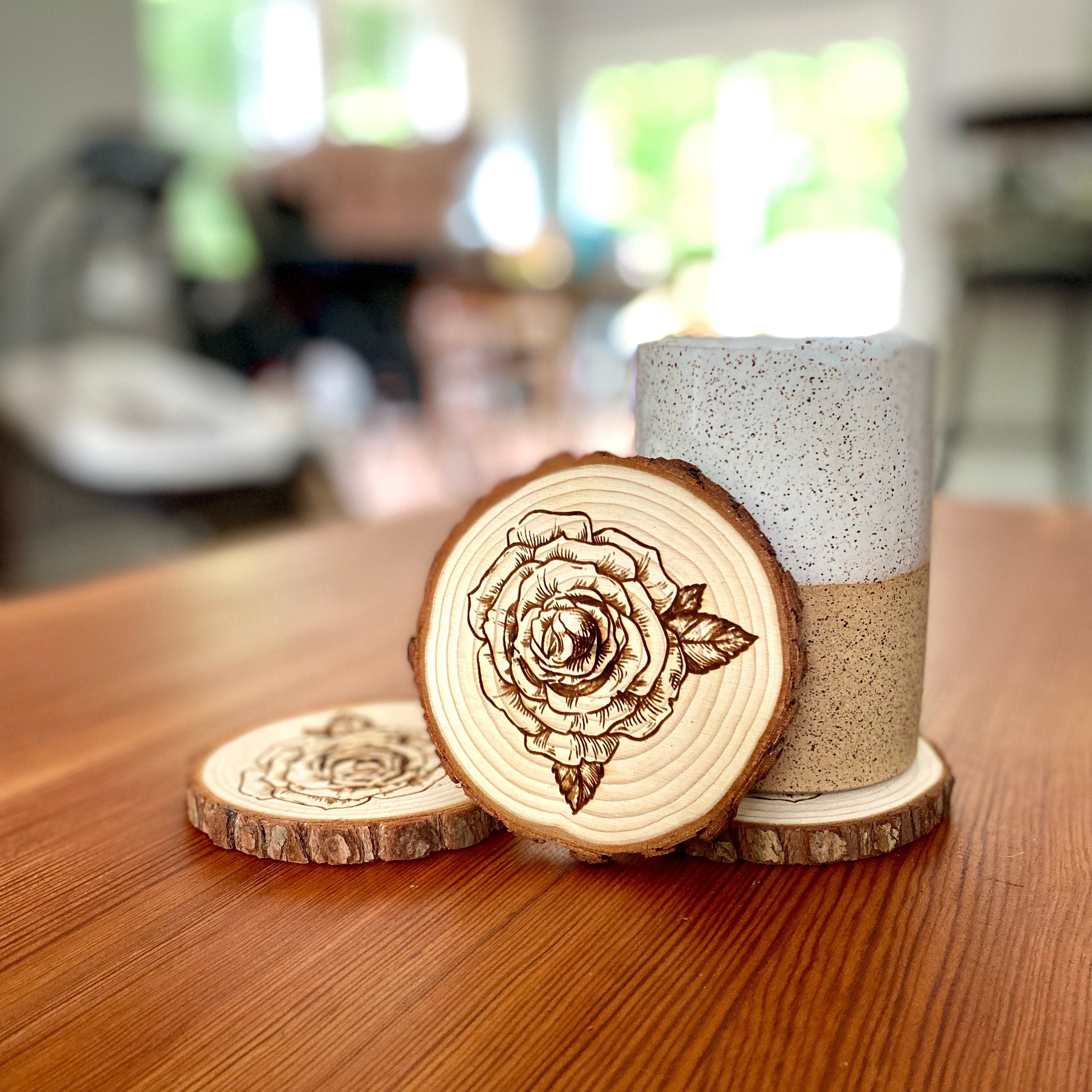 A set of four rose engraved wood coasters, showcasing intricate rose designs on a natural wood surface, ideal for home decor.