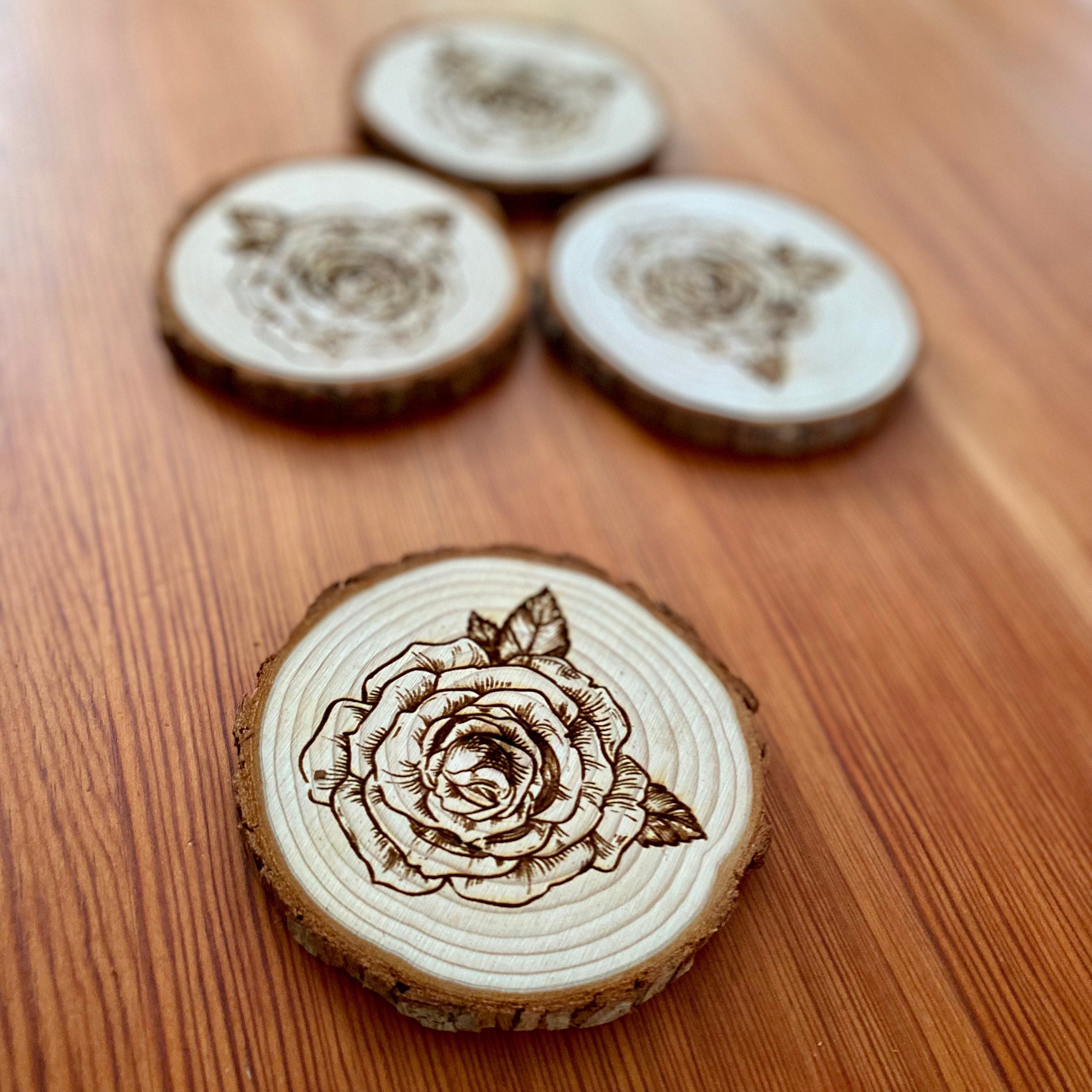 A set of four rose engraved wood coasters, showcasing intricate rose designs on a natural wood surface, ideal for home decor.