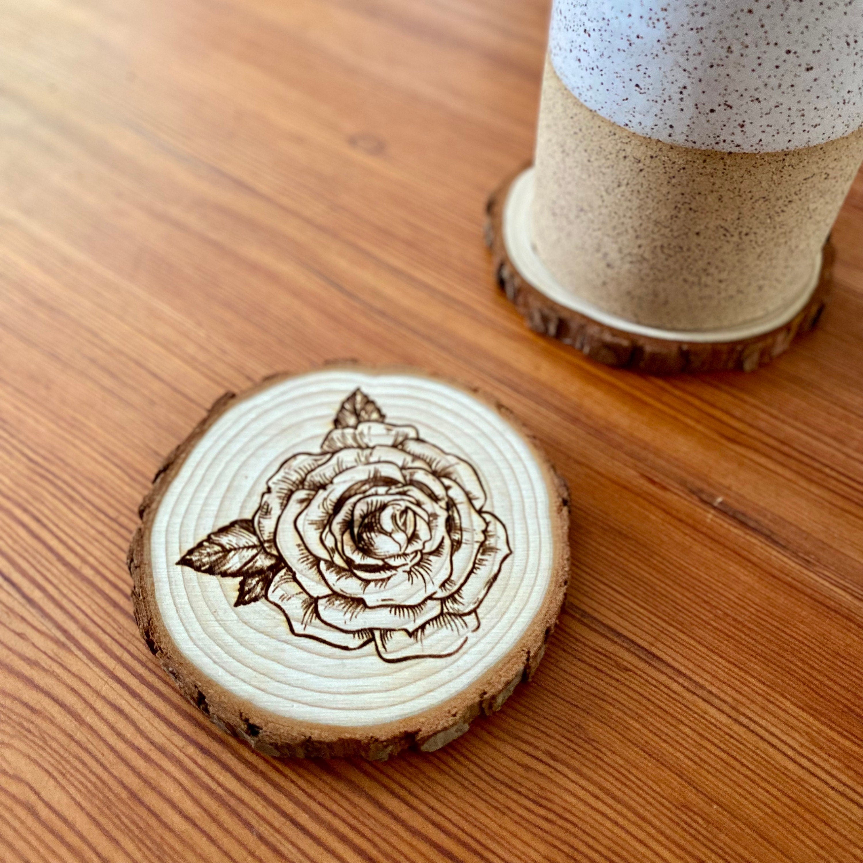 A set of four rose engraved wood coasters, showcasing intricate rose designs on a natural wood surface, ideal for home decor.