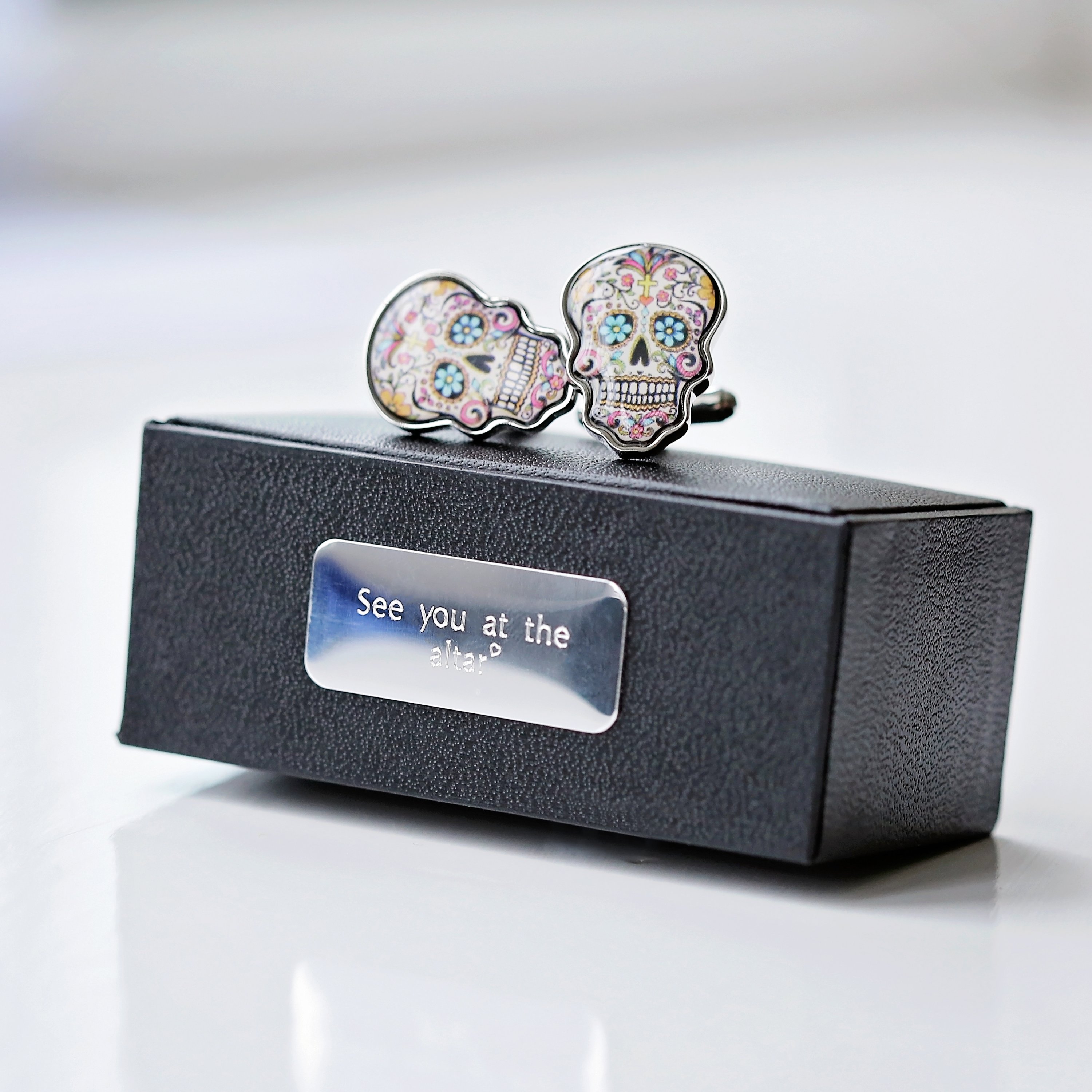 A pair of stylish skull cufflinks displayed in a luxury engraved box, showcasing intricate details and personalization options.