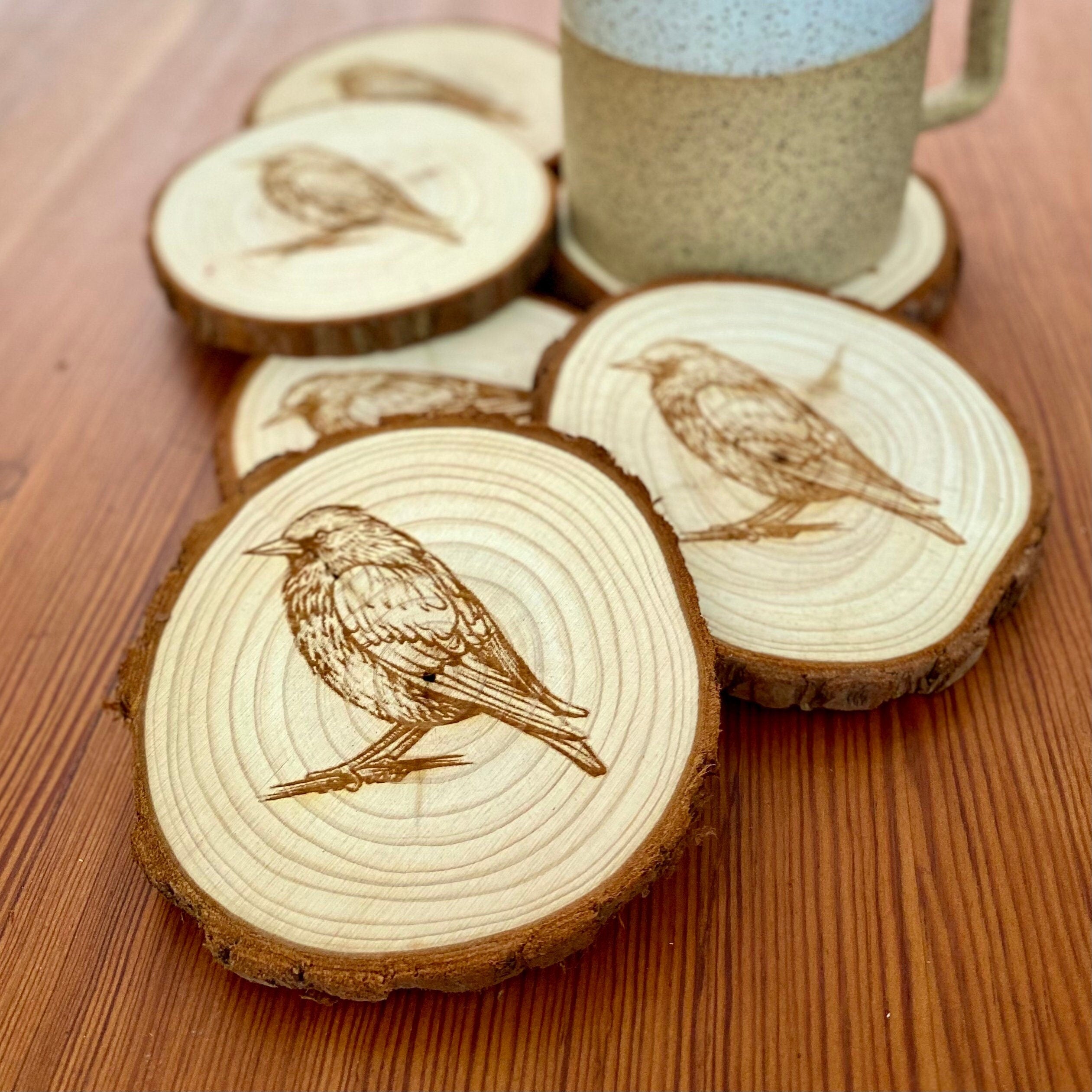 A set of four laser engraved wood coasters featuring starling bird illustrations, showcasing their natural wood finish and intricate designs.