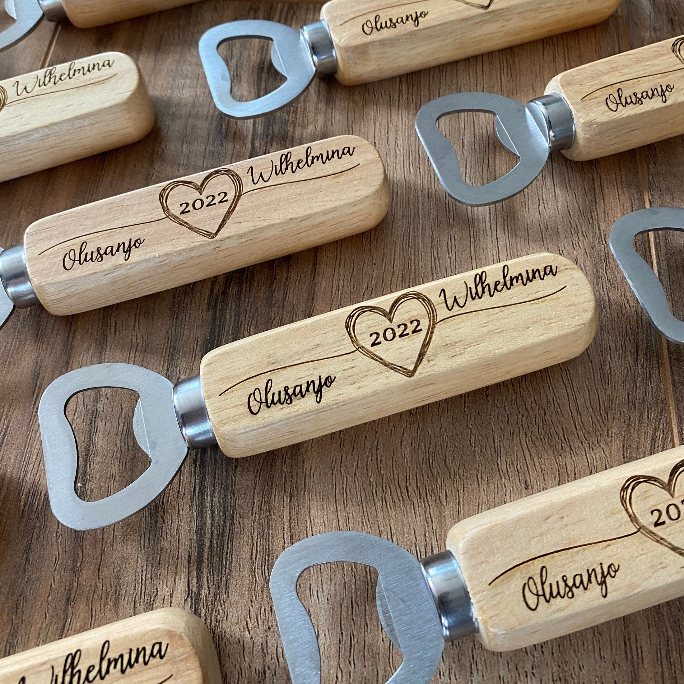 Personalized wooden bottle opener with engraved names and heart design, perfect for rustic wedding favors.