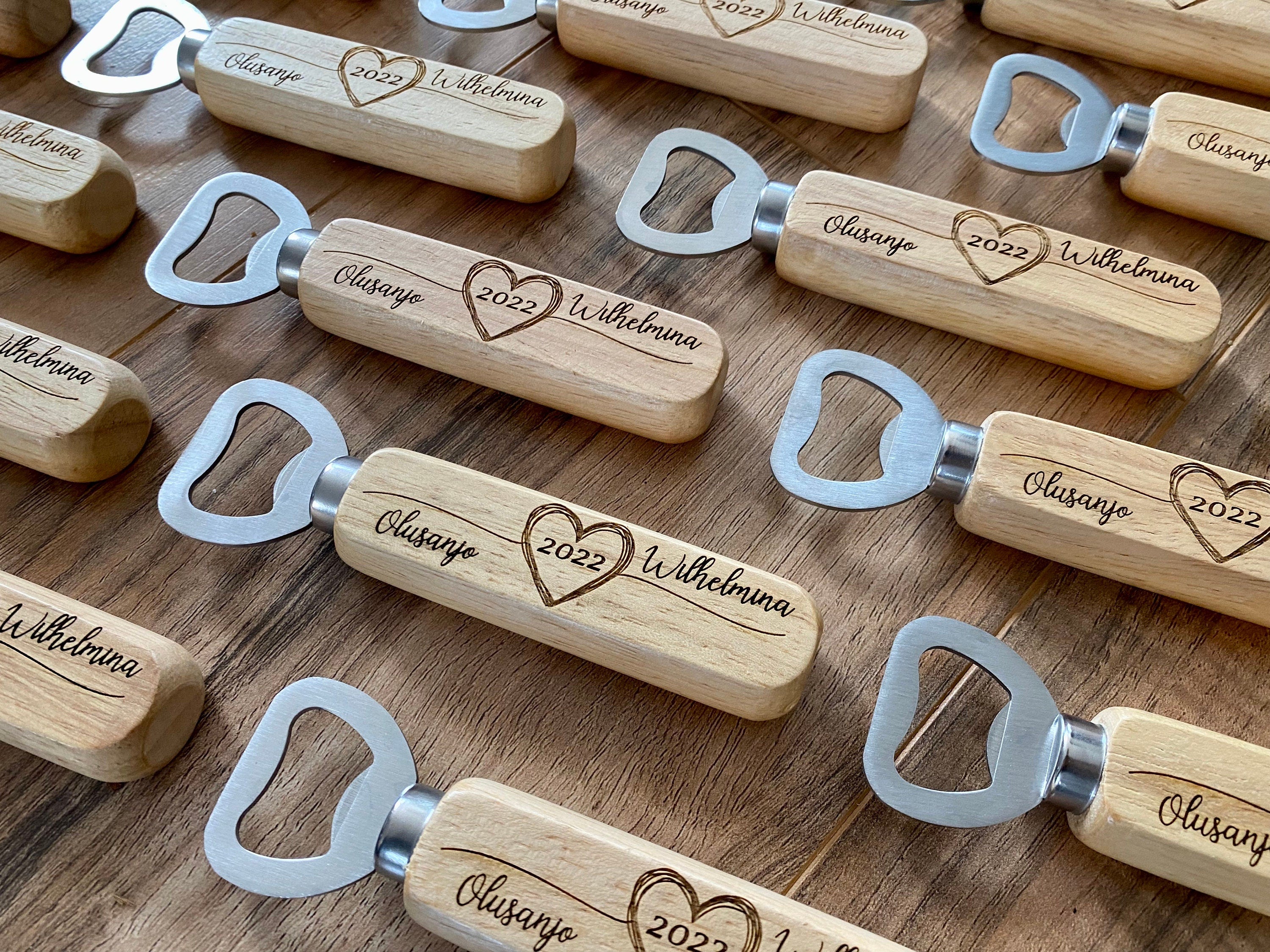 Personalized wooden bottle opener with engraved names and heart design, perfect for rustic wedding favors.