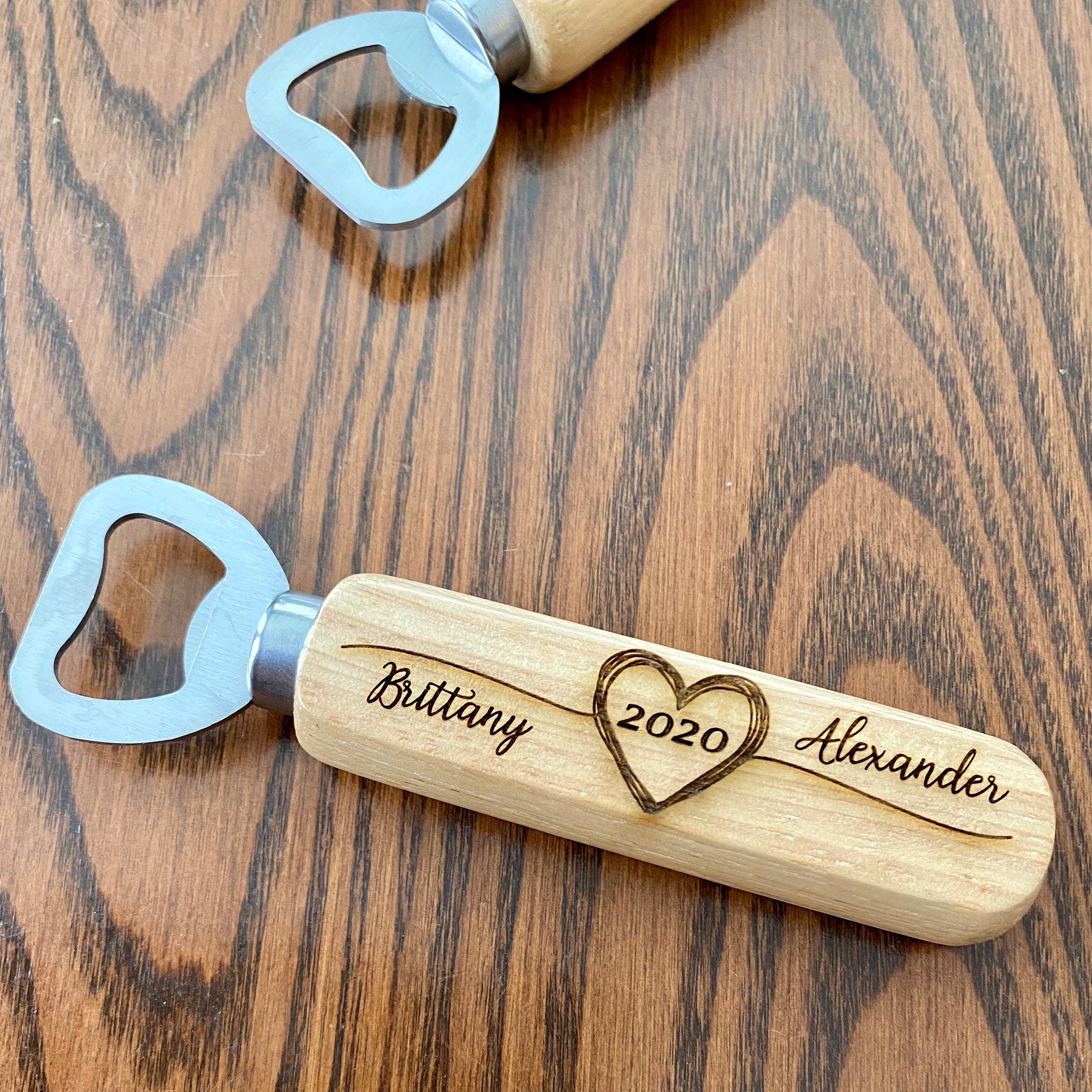 Personalized wooden bottle opener with engraved names and heart design, perfect for rustic wedding favors.