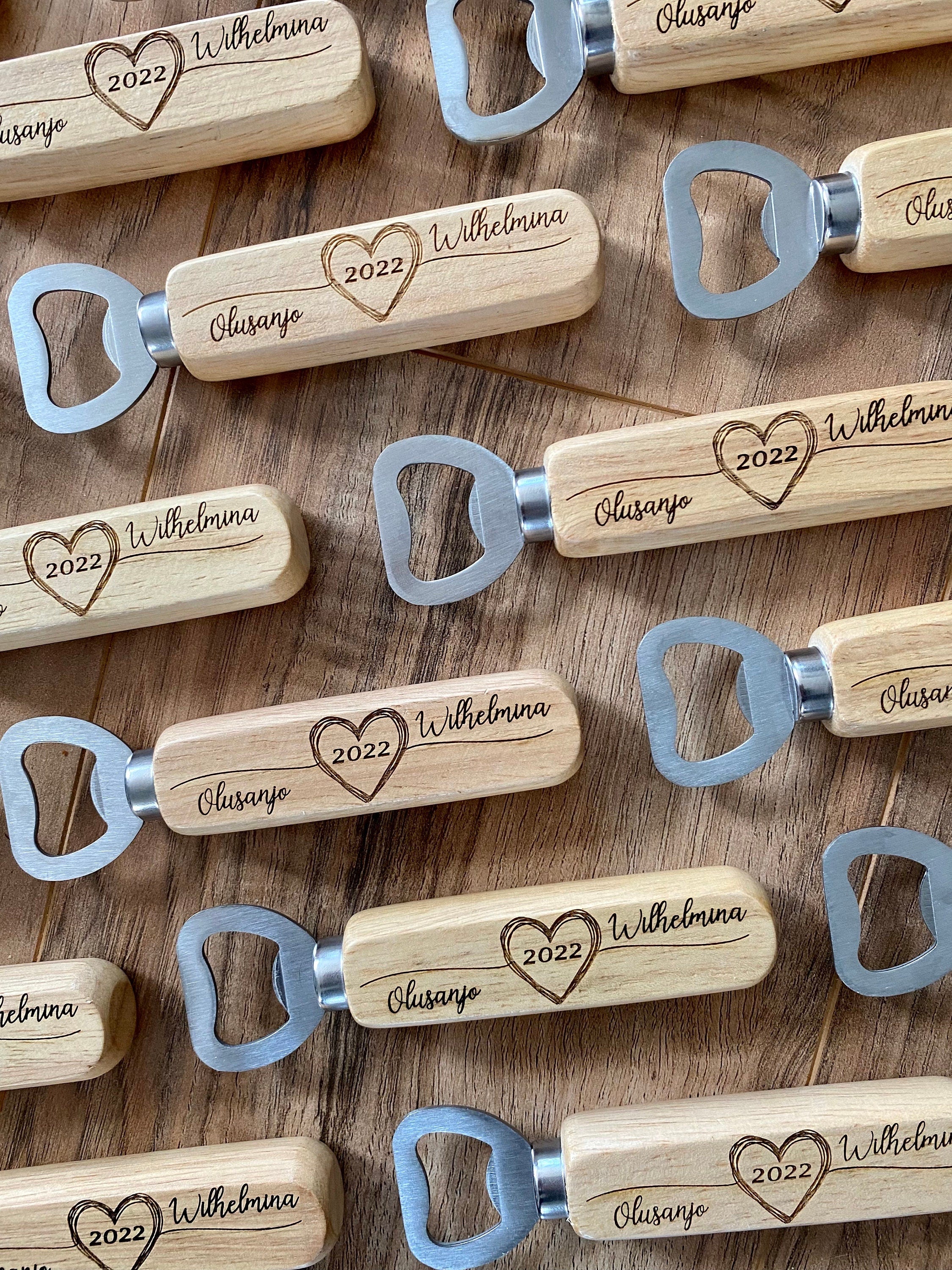 Personalized wooden bottle opener with engraved names and heart design, perfect for rustic wedding favors.