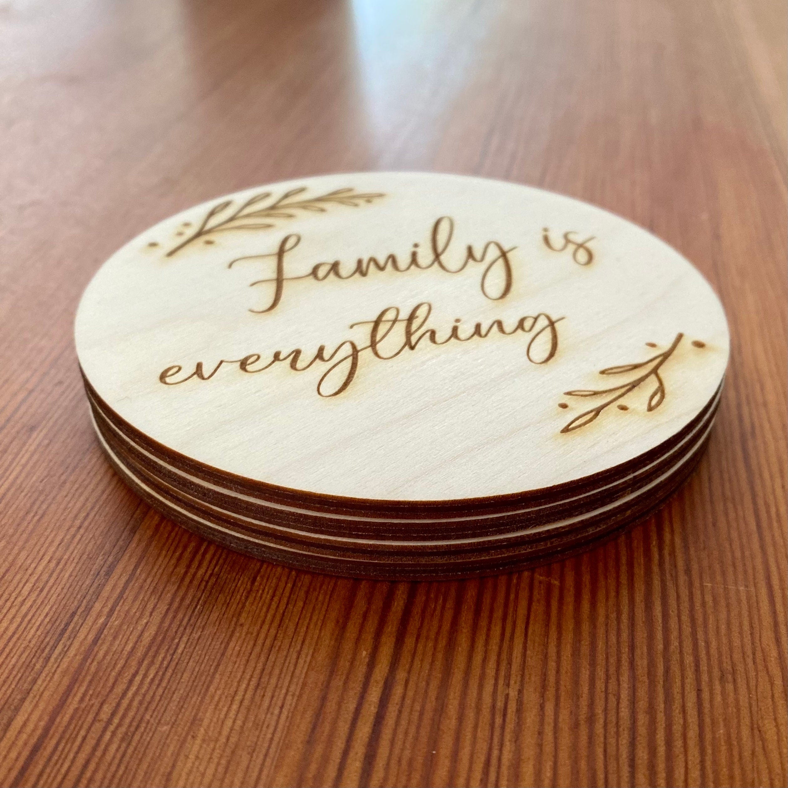 A set of wooden coasters engraved with 'Family is everything' and a leaf border, showcasing their rustic charm and high-quality finish.