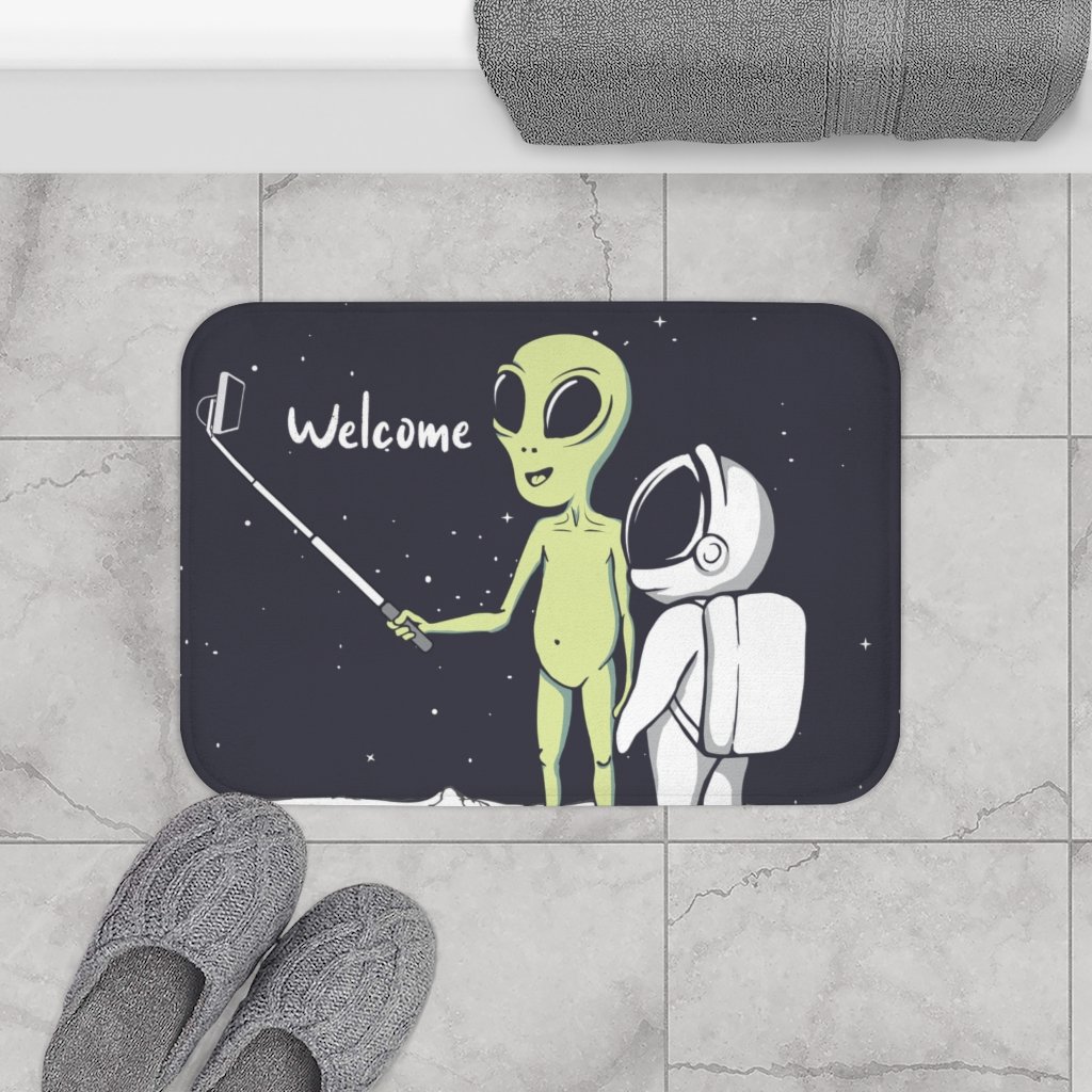 A colorful bath mat featuring a playful alien taking a selfie, designed with anti-slip backing and durable edges.