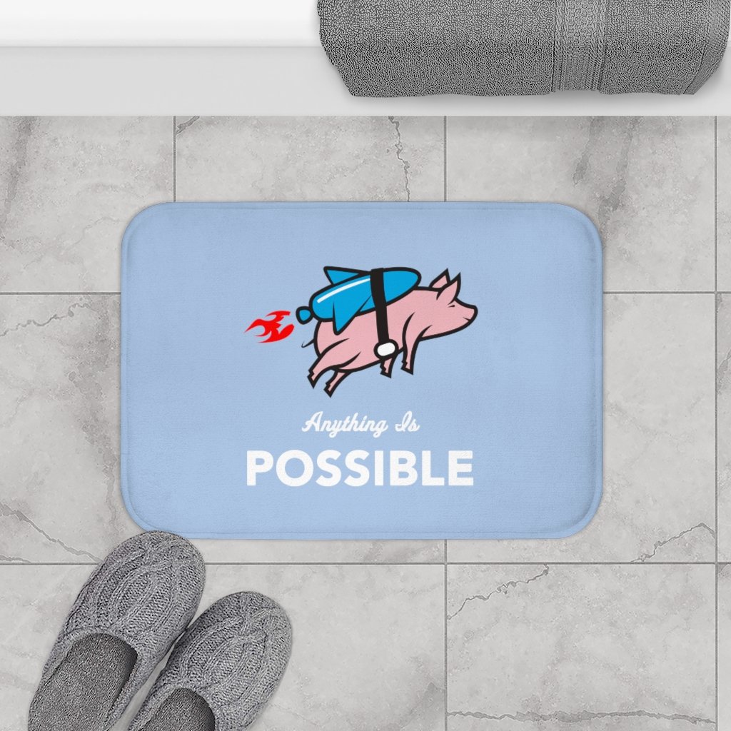 A colorful bath mat featuring a whimsical flying pig with a rocket, designed for safety with anti-slip backing and soft microfiber material.