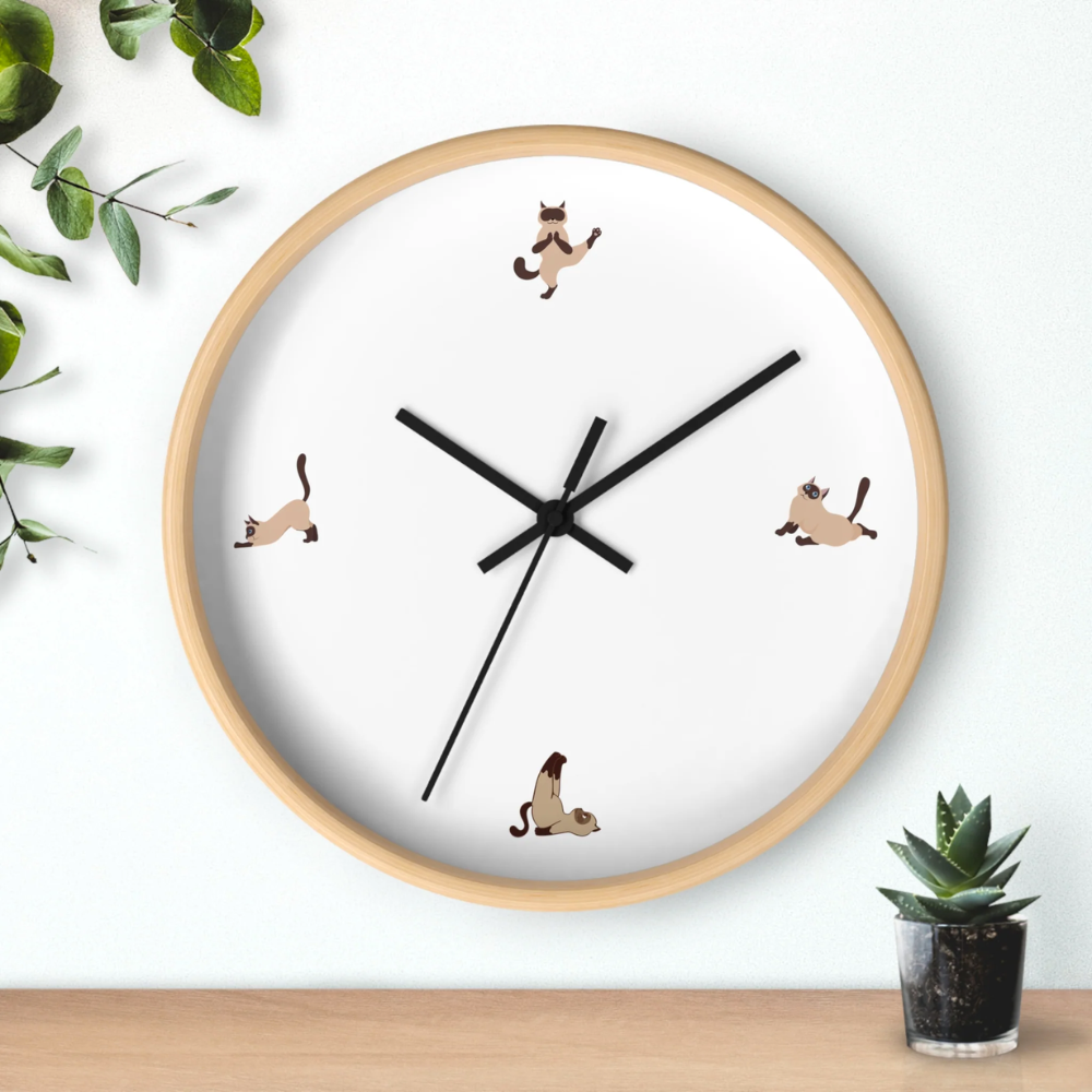 A whimsical wall clock featuring a cat doing yoga poses, set in a wooden frame with a clear plexiglass face, perfect for indoor decor.