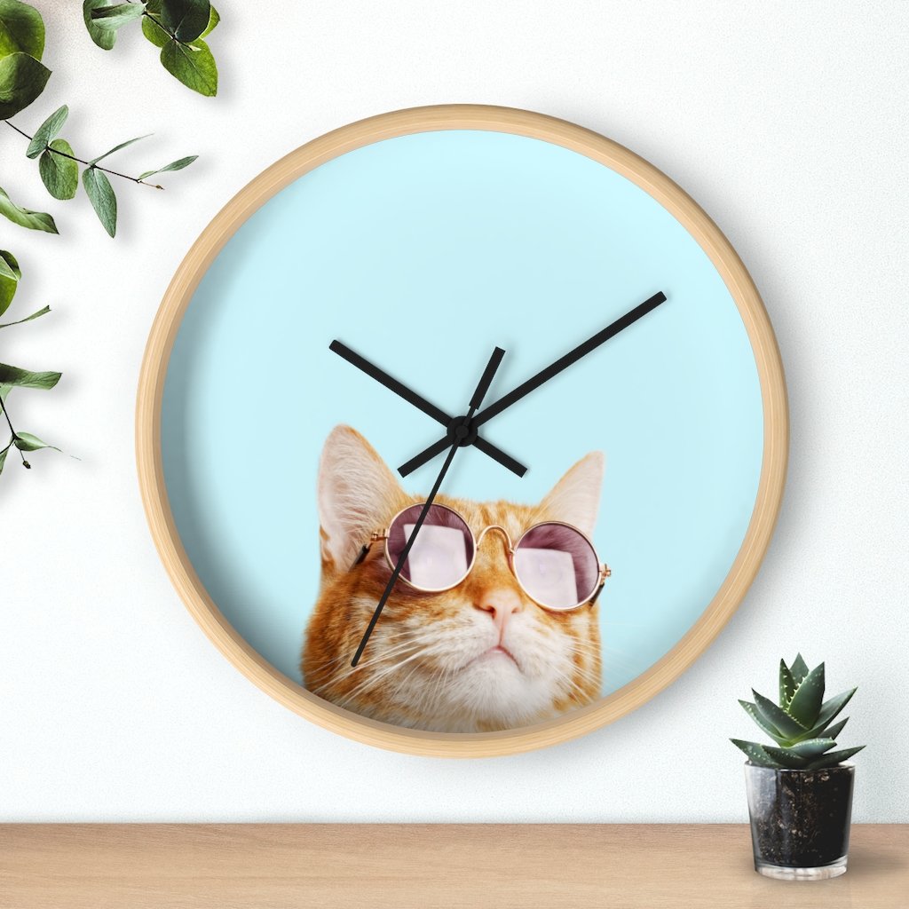 A whimsical wall clock featuring a cat design with a wooden frame and plexiglass face, ideal for indoor use.