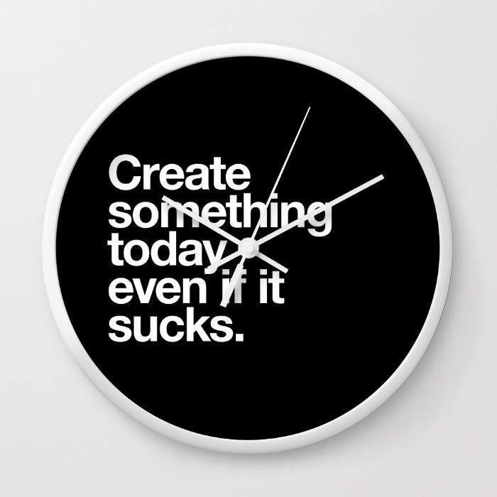 A stylish wall clock with a motivational quote, available in black or white frames, featuring a clear plexiglass face and contrasting hands.