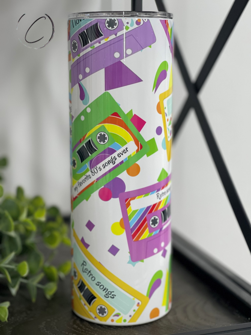 A colorful 20oz skinny tumbler featuring a retro 80's cassette tape design, complete with a reusable straw.