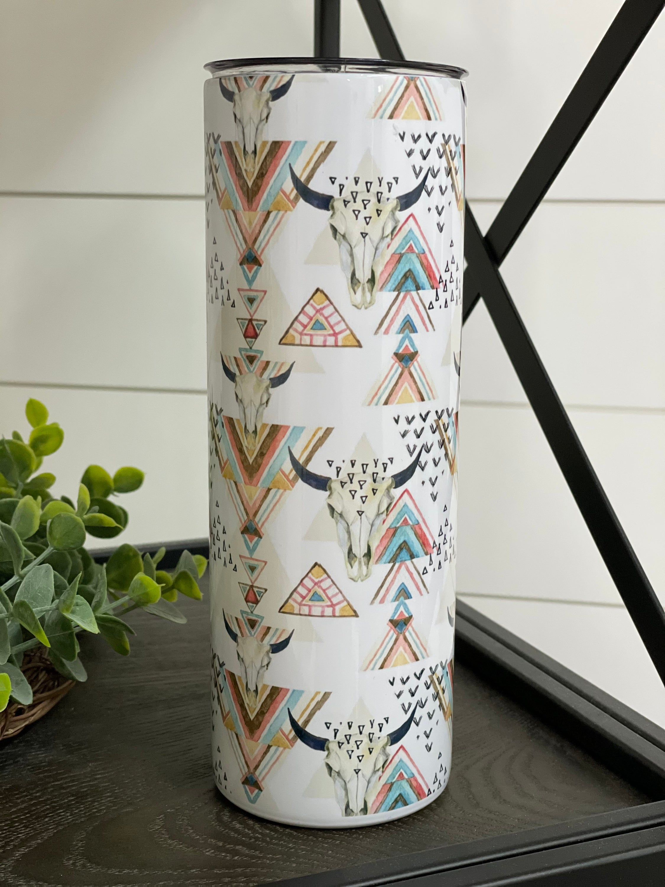 Aztec Bull Skull 20oz Skinny Tumbler featuring vibrant artwork and a reusable straw, perfect for hot and cold beverages.