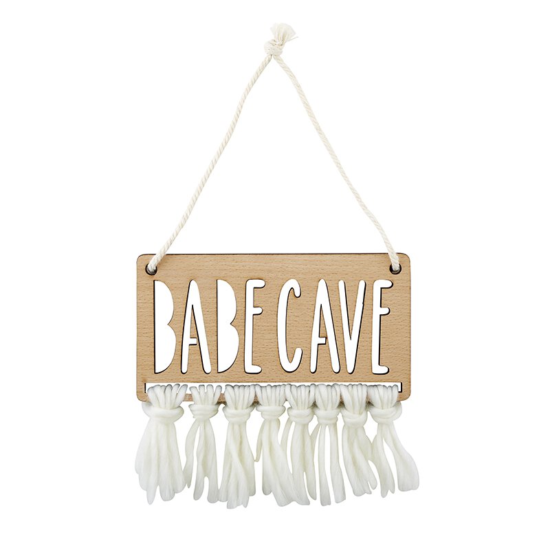 Babe Cave Wood Door Sign made from natural beech wood with humorous text and fringe embellishment, hanging on a wall.