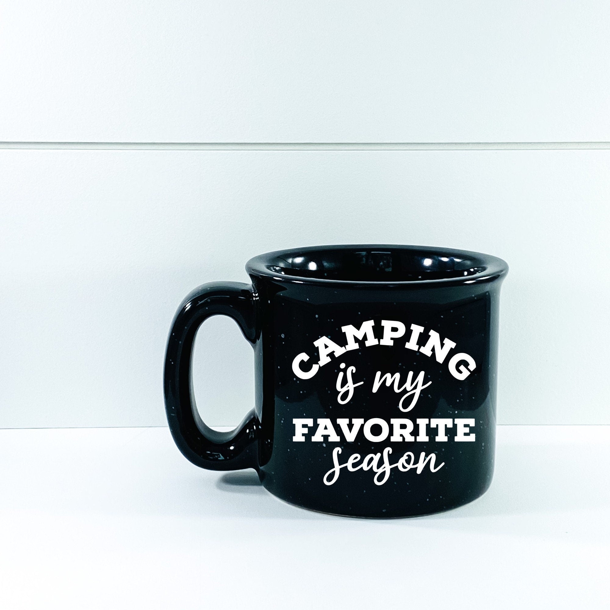 Ceramic campfire mug with 'Camping Is My Favorite Season' design, perfect for outdoor enthusiasts.