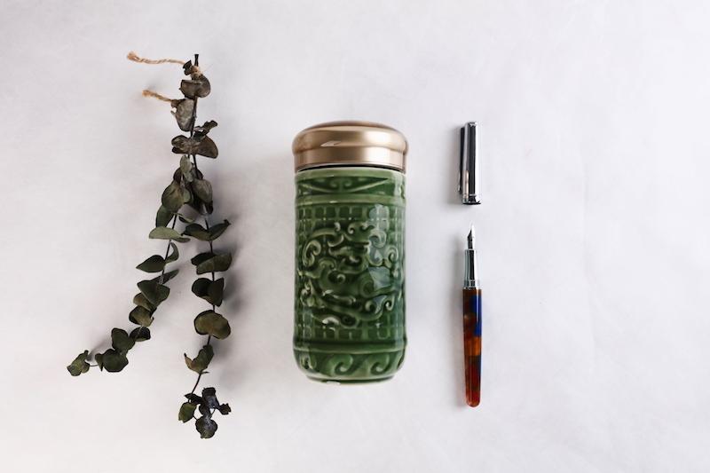 The Determination Tumbler featuring Persimmon Calyx and Jade Dragon patterns, made of tourmaline ceramic with an acrylic resin lid.