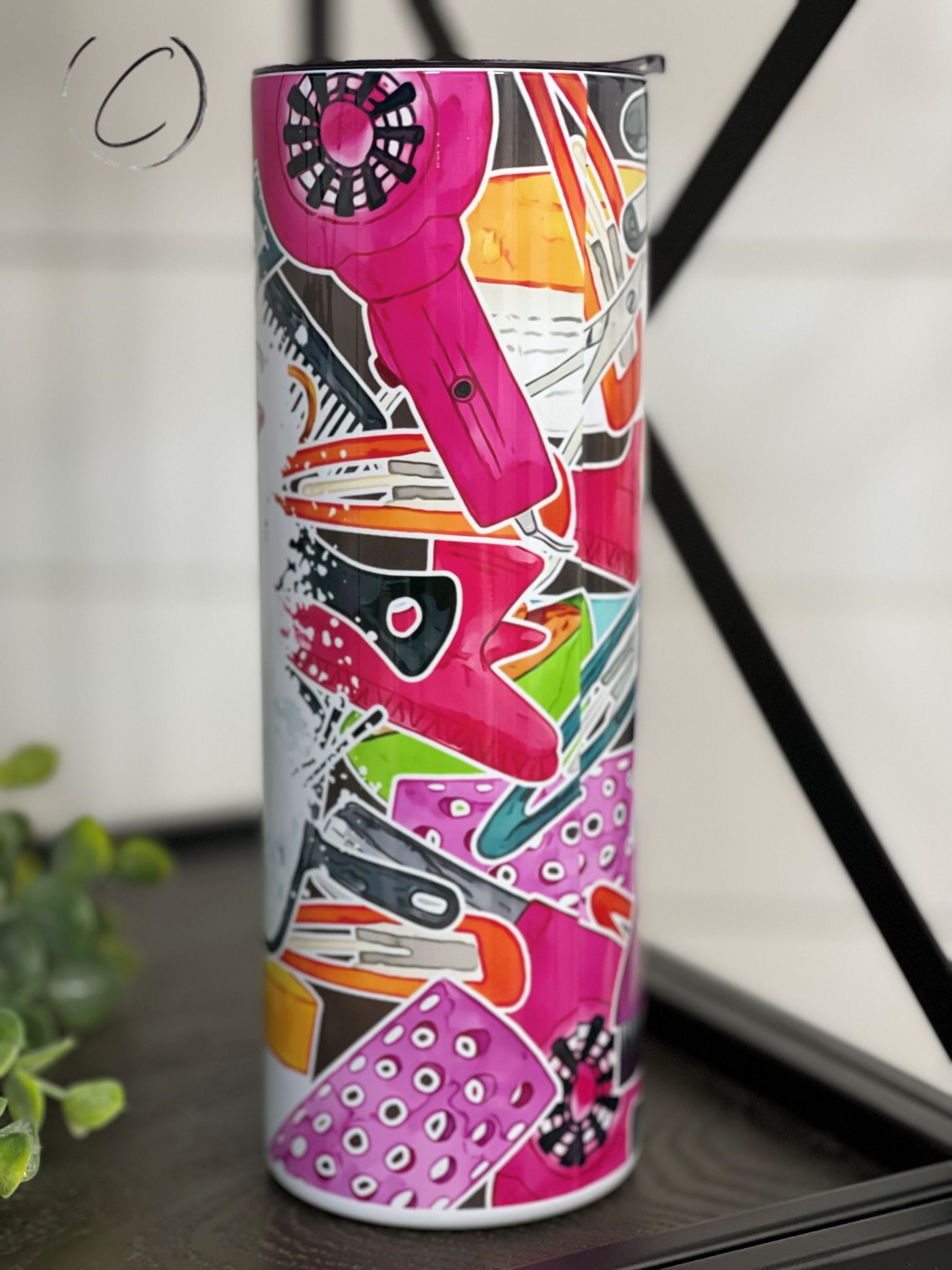 A stylish #HairHuslter 20oz skinny tumbler featuring a vibrant full wrap design, complete with a reusable straw.