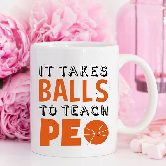 A humorous coffee mug featuring the phrase 'It Takes Balls To Teach PE', crafted from high-quality ceramic, perfect for teachers and sports enthusiasts.