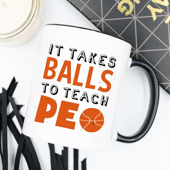 A humorous coffee mug featuring the phrase 'It Takes Balls To Teach PE', crafted from high-quality ceramic, perfect for teachers and sports enthusiasts.