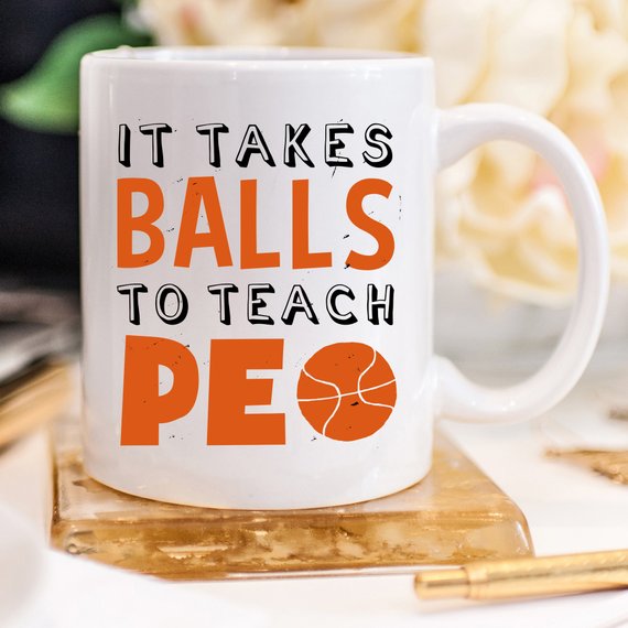 A humorous coffee mug featuring the phrase 'It Takes Balls To Teach PE', crafted from high-quality ceramic, perfect for teachers and sports enthusiasts.