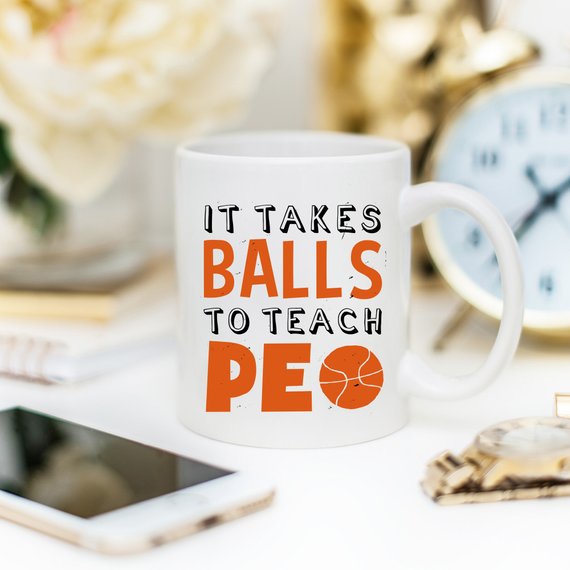 A humorous coffee mug featuring the phrase 'It Takes Balls To Teach PE', crafted from high-quality ceramic, perfect for teachers and sports enthusiasts.