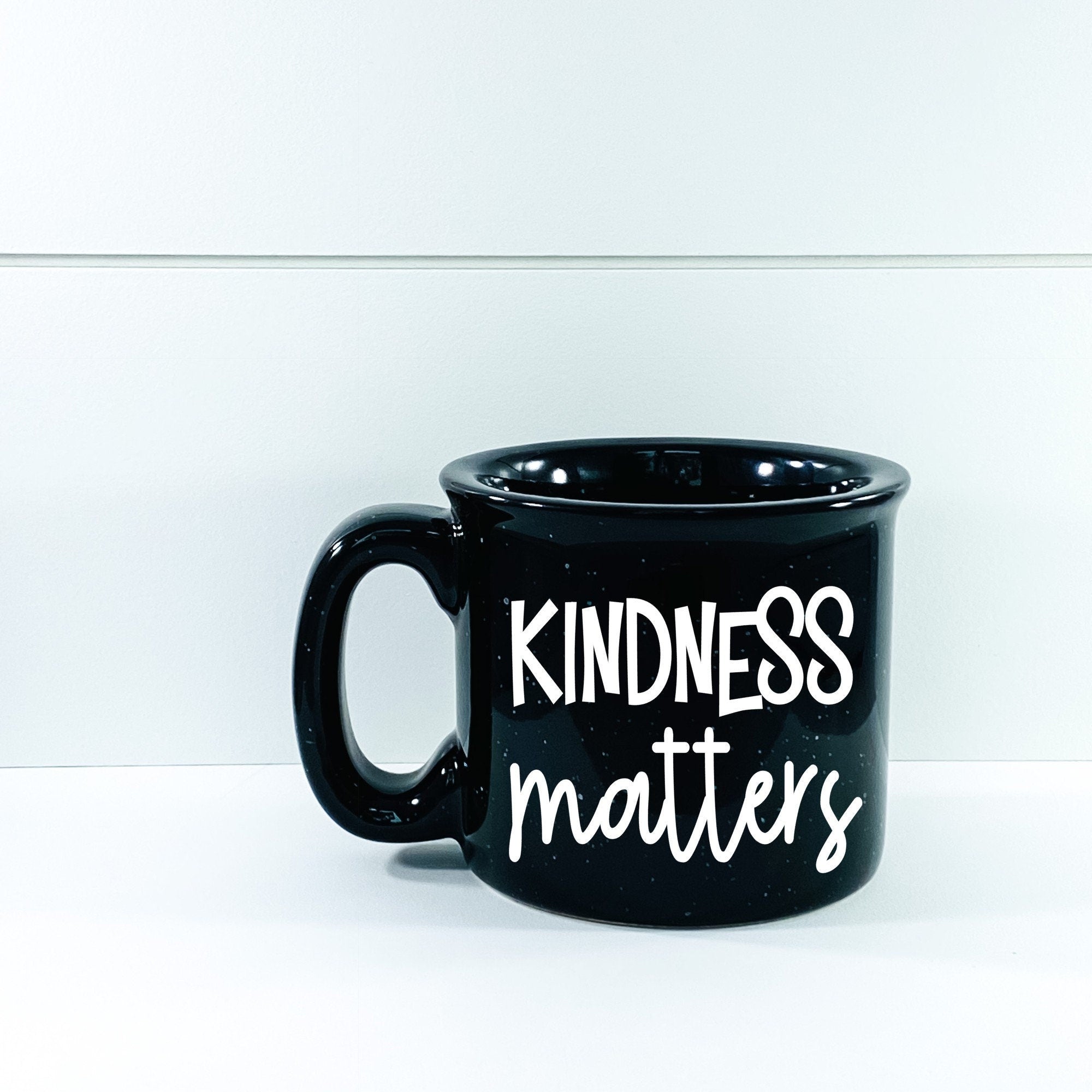 A stylish Kindness Matters Campfire Mug with a unique vinyl design, perfect for enjoying hot beverages.