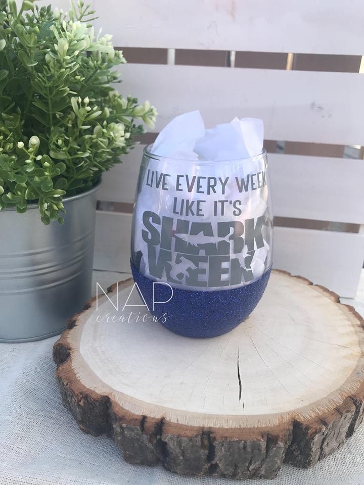 A vibrant stemless wine glass with glitter, featuring the phrase 'Live Every Week Like It's Shark Week' printed on one side.