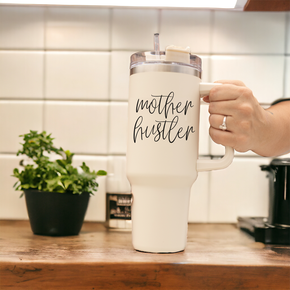 Mother Hustler 40oz tumbler with matte finish, featuring a bold black graphic on a cream exterior, designed for busy moms.