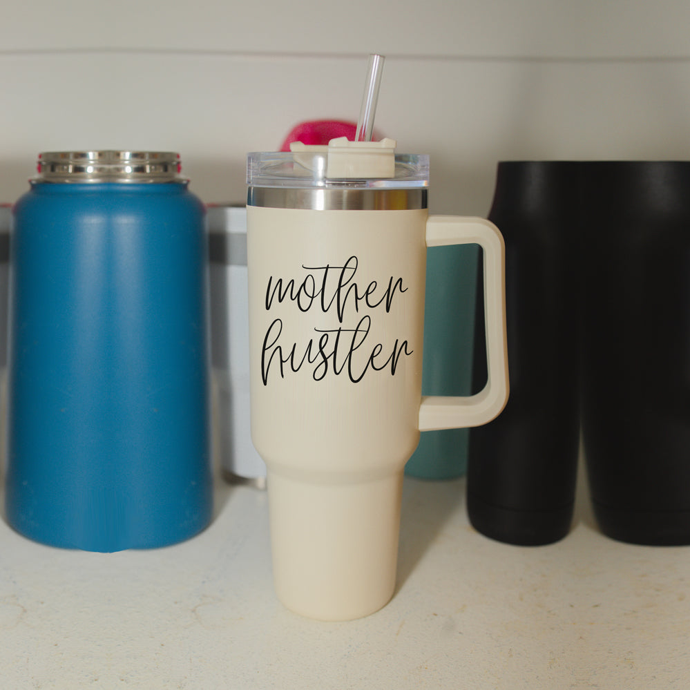 Mother Hustler 40oz tumbler with matte finish, featuring a bold black graphic on a cream exterior, designed for busy moms.