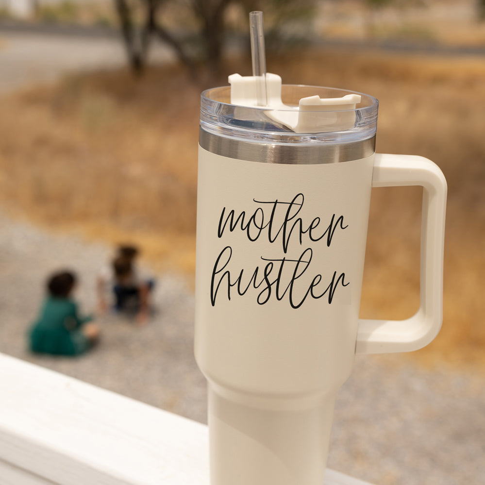 Mother Hustler 40oz tumbler with matte finish, featuring a bold black graphic on a cream exterior, designed for busy moms.