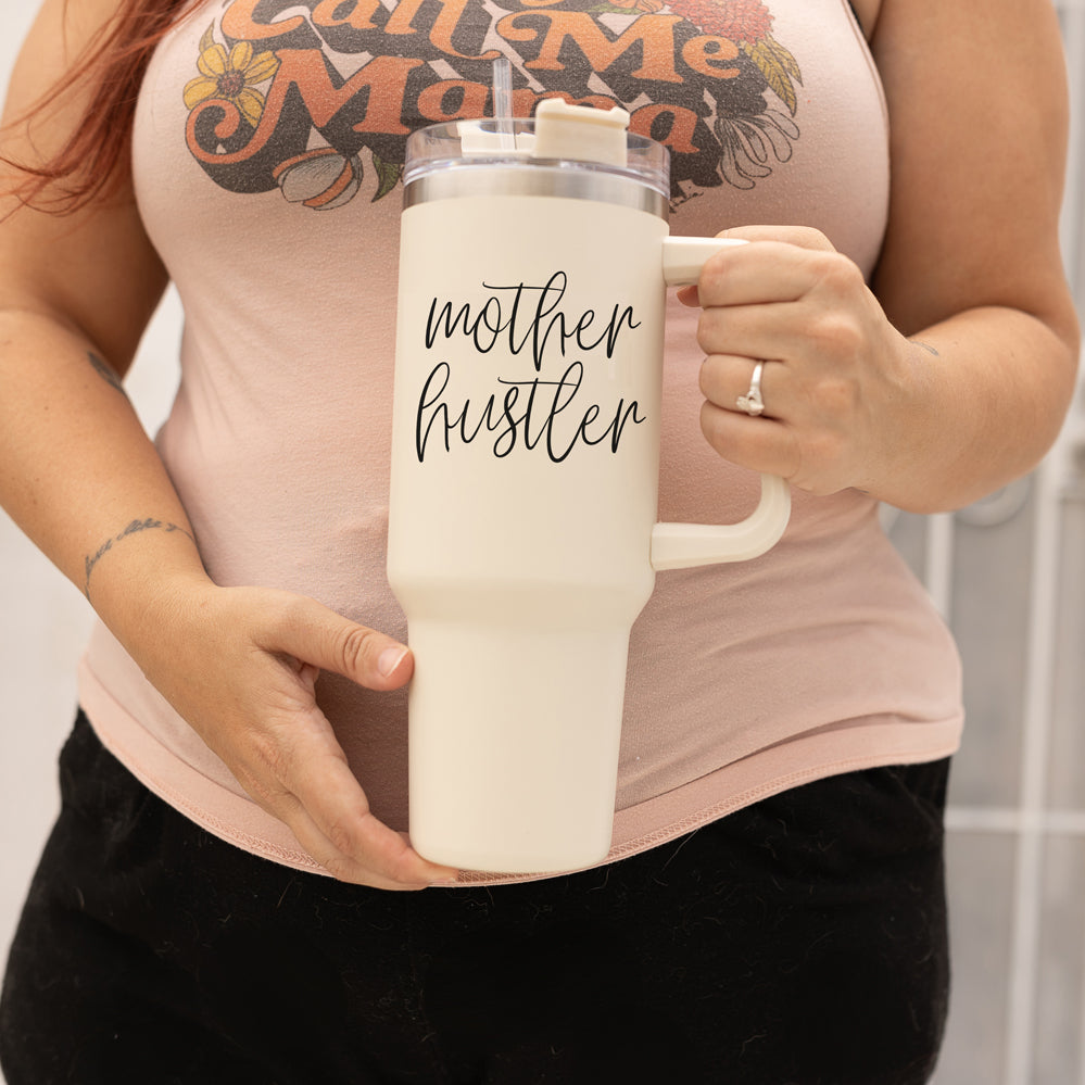 Mother Hustler 40oz tumbler with matte finish, featuring a bold black graphic on a cream exterior, designed for busy moms.