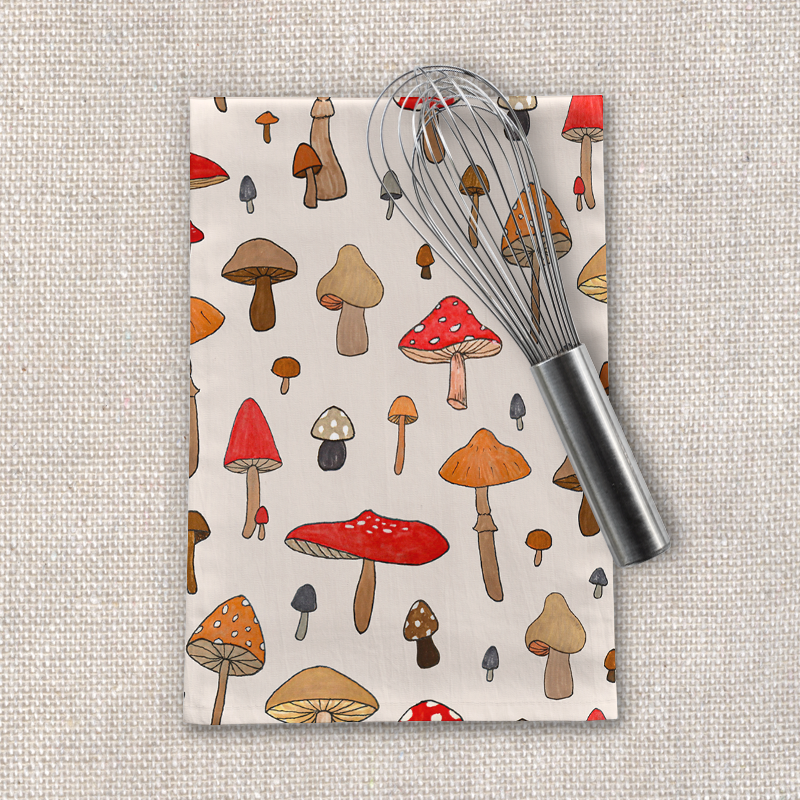 A cozy mushroom-themed tea towel made of cotton twill, featuring a whimsical design and hemmed edges, perfect for kitchen use.