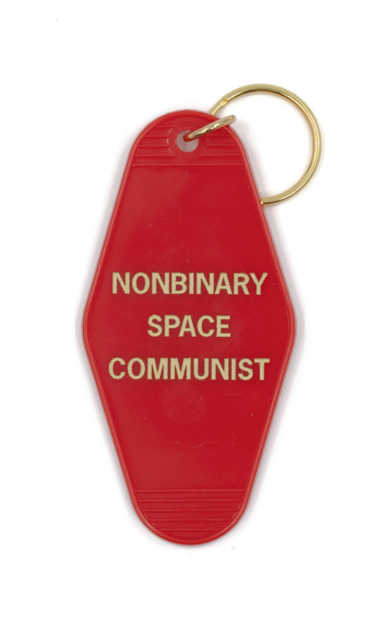 Nonbinary Space Communist Motel Style Keychain in vibrant red with gold lettering, featuring a split ring for key attachment.