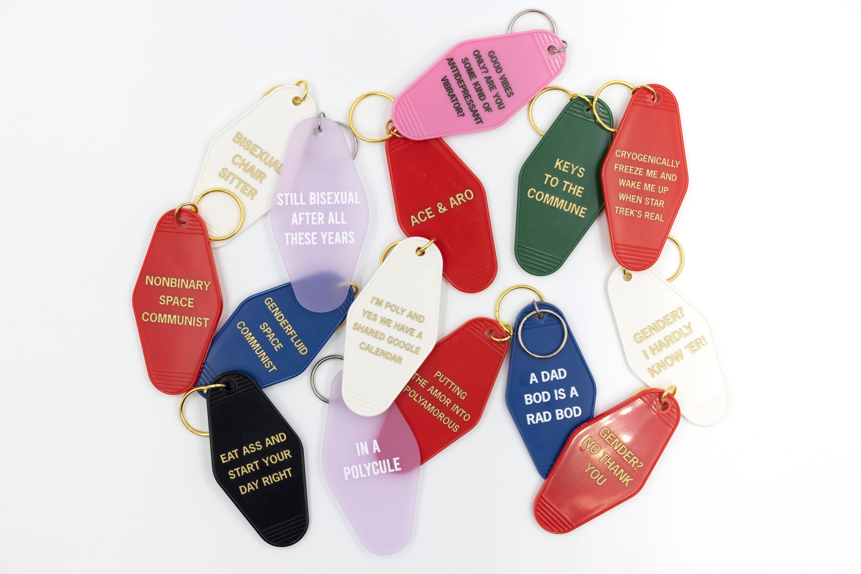 Nonbinary Space Communist Motel Style Keychain in vibrant red with gold lettering, featuring a split ring for key attachment.