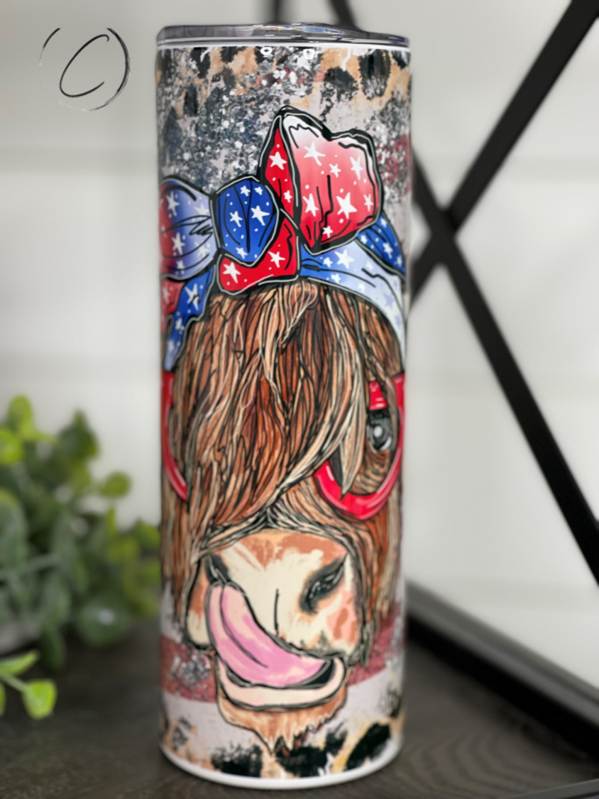 A 20oz skinny tumbler featuring a vibrant patriotic Highland cow design, perfect for hot and cold beverages.