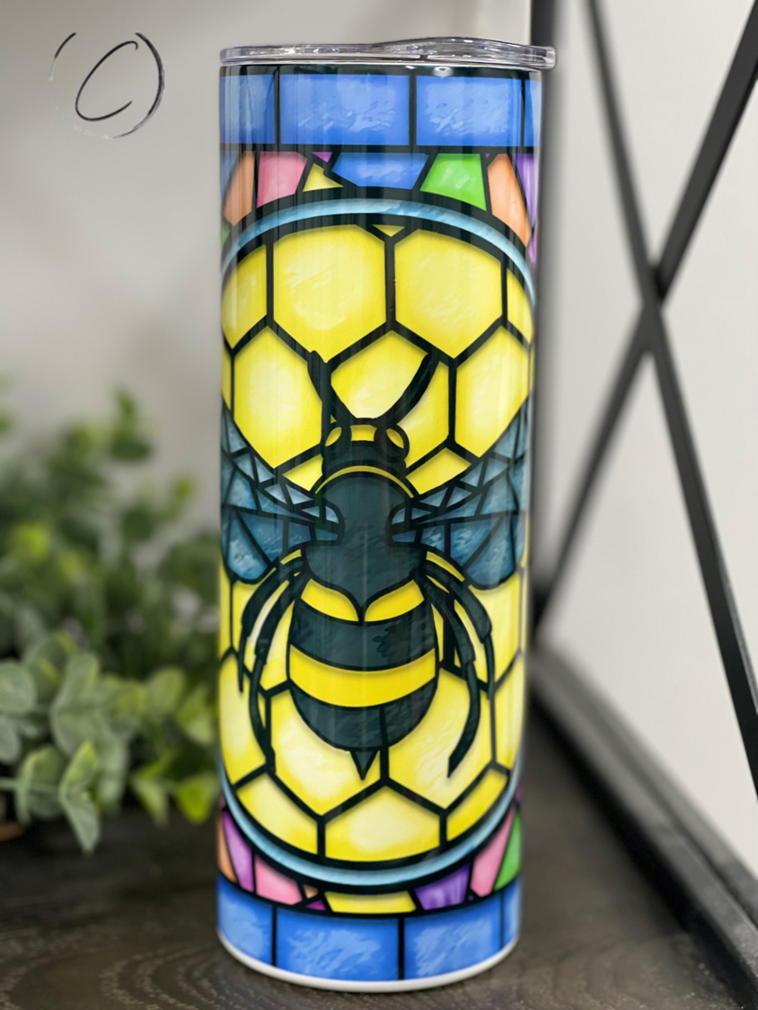 A stylish 20oz skinny tumbler featuring a vibrant stained glass bee design, perfect for drinks on the go.