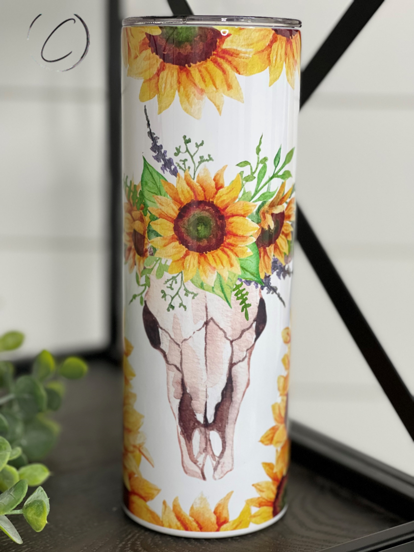 A stylish 20oz skinny tumbler featuring a sunflower and bull skull design, perfect for hot and cold beverages.