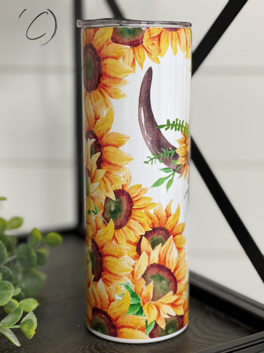 A stylish 20oz skinny tumbler featuring a sunflower and bull skull design, perfect for hot and cold beverages.