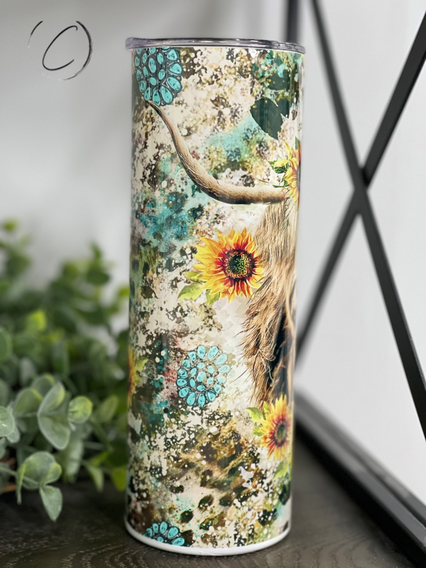 A stylish 20oz skinny tumbler featuring a Highland cow surrounded by vibrant sunflowers, perfect for drinks on the go.