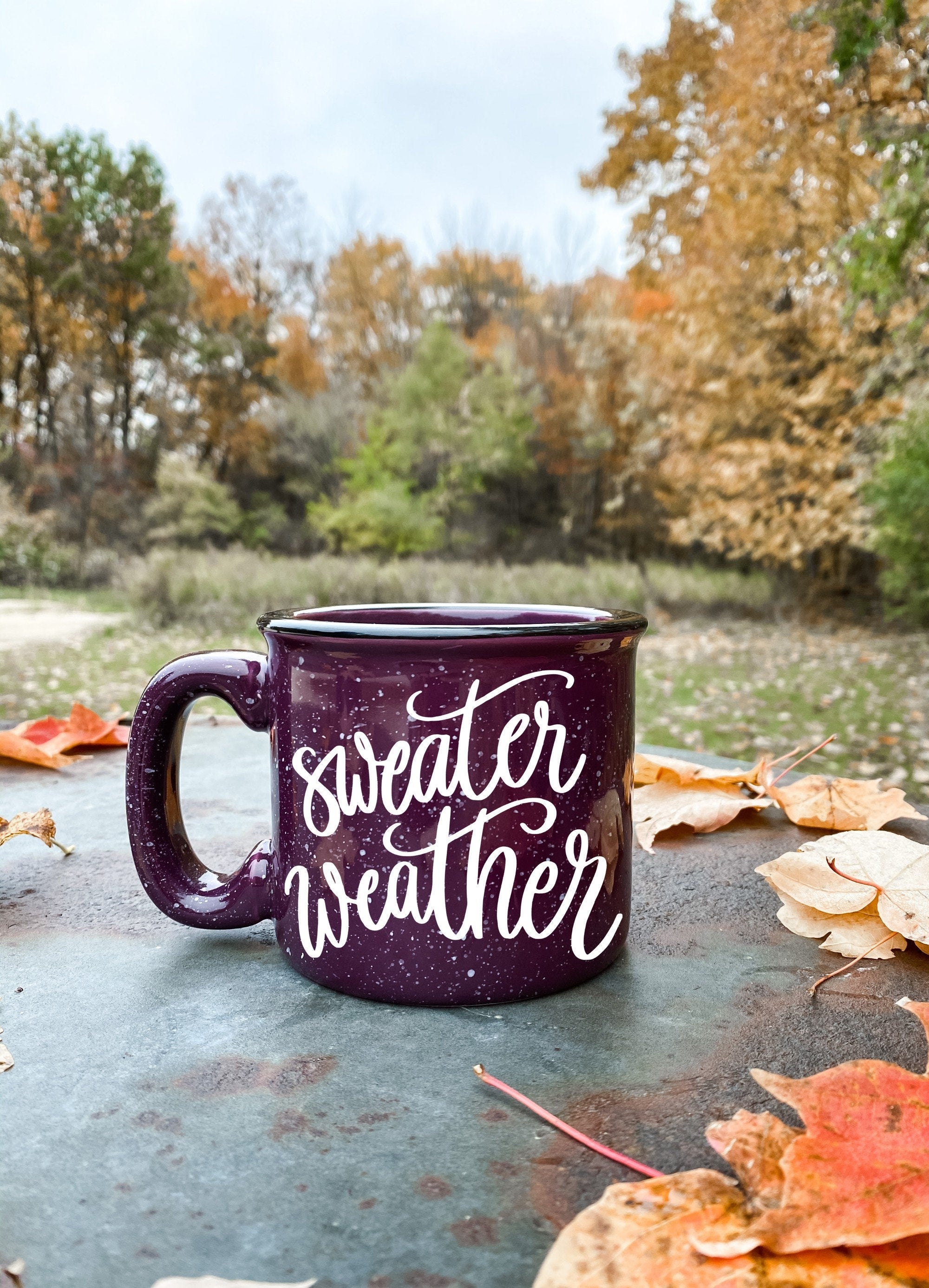 A cozy ceramic campfire mug with a 'Sweater Weather' design, perfect for warm beverages.