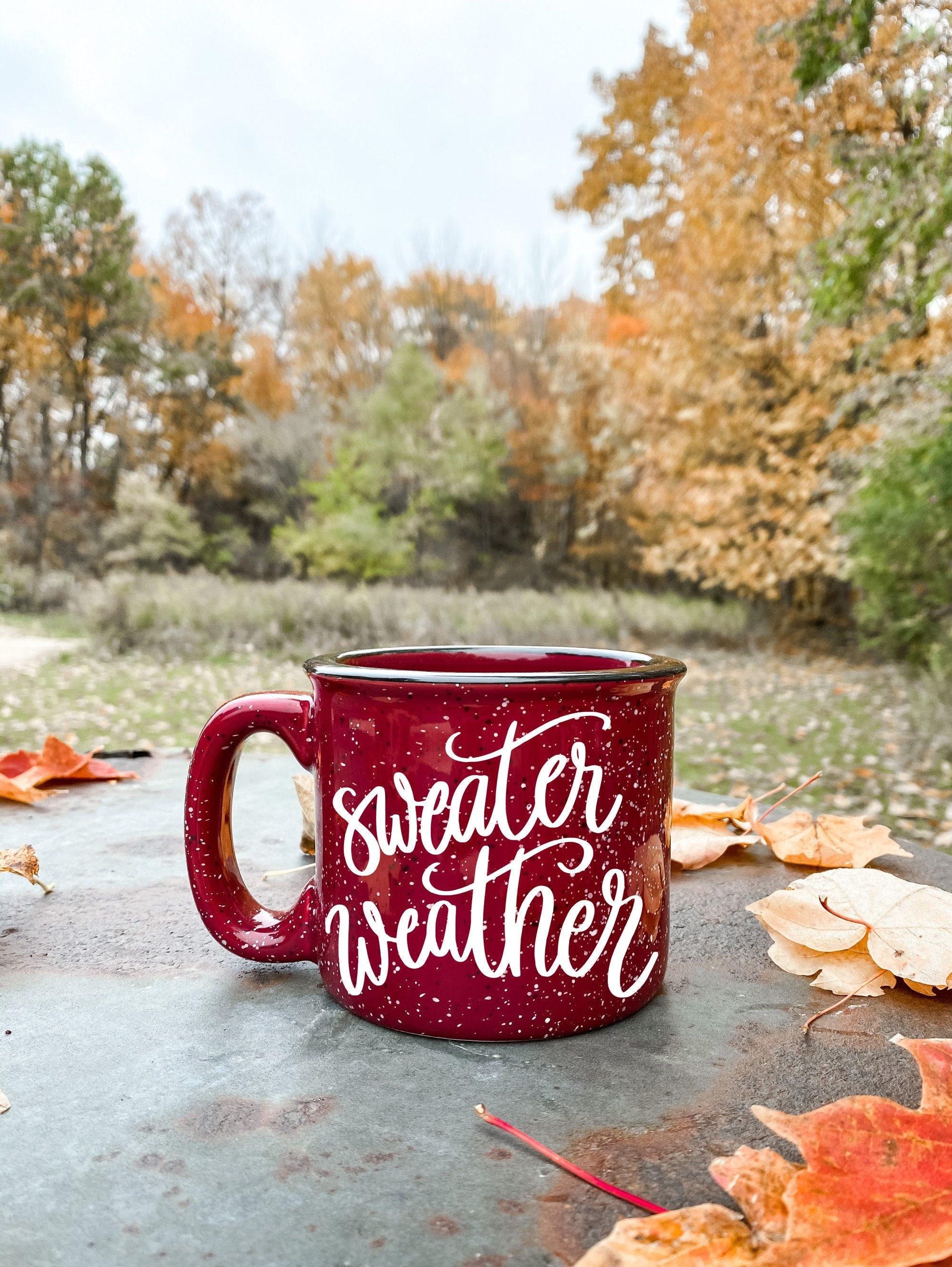 A cozy ceramic campfire mug with a 'Sweater Weather' design, perfect for warm beverages.