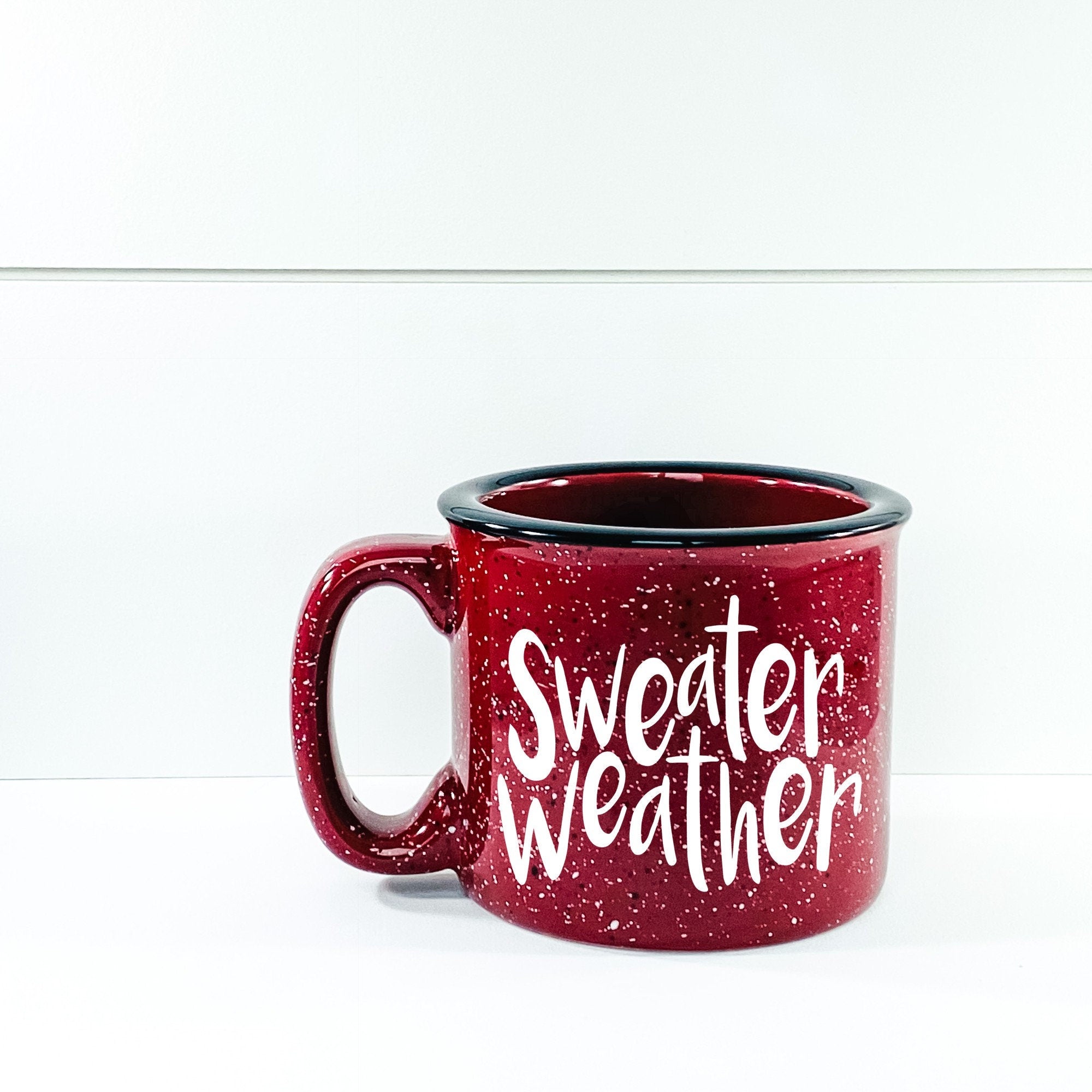 A cozy ceramic campfire mug with a 'Sweater Weather' design, perfect for warm beverages.