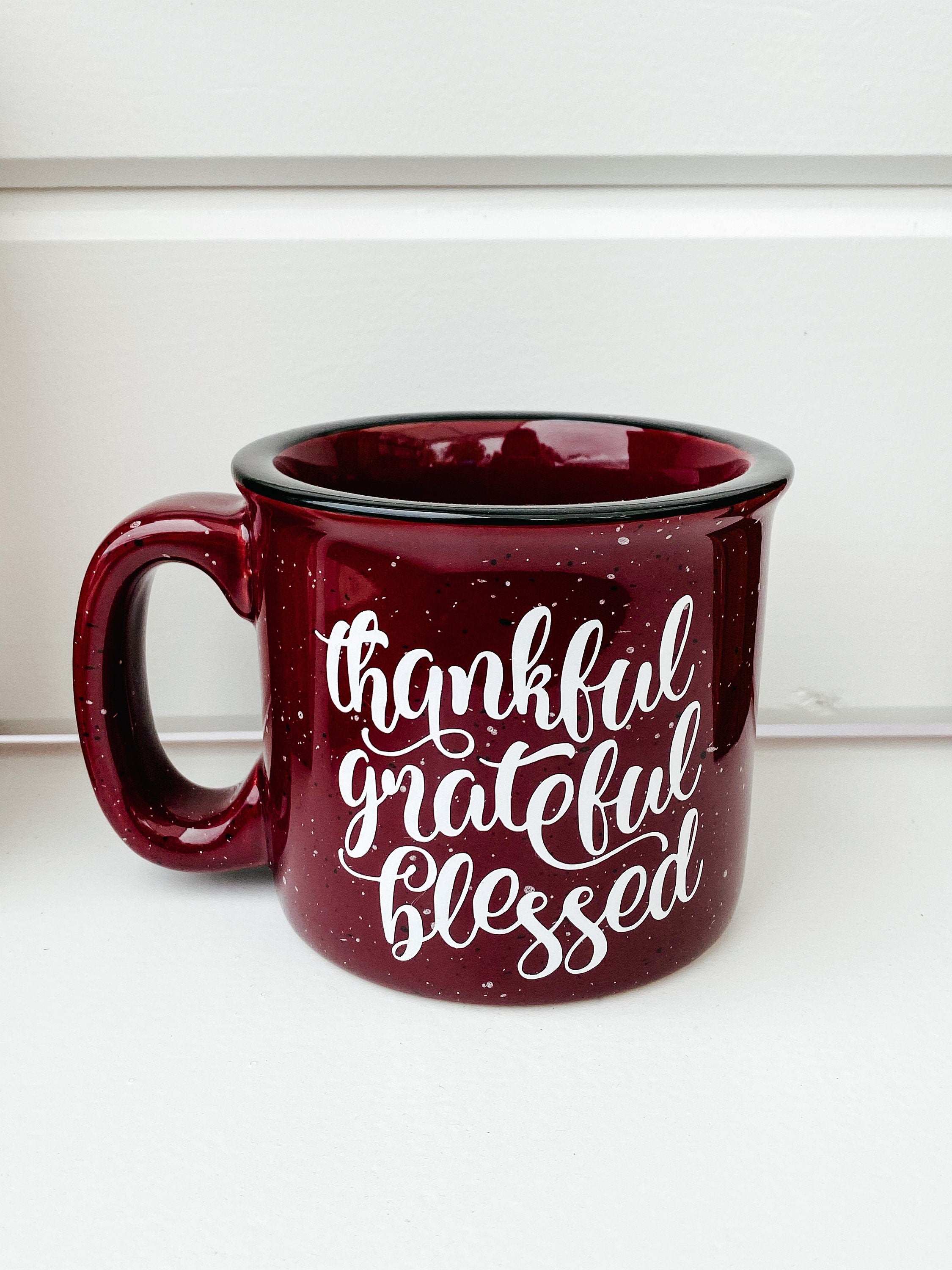 A ceramic coffee mug featuring the phrase 'Thankful Grateful and Blessed' printed on one side, showcasing a stylish design.