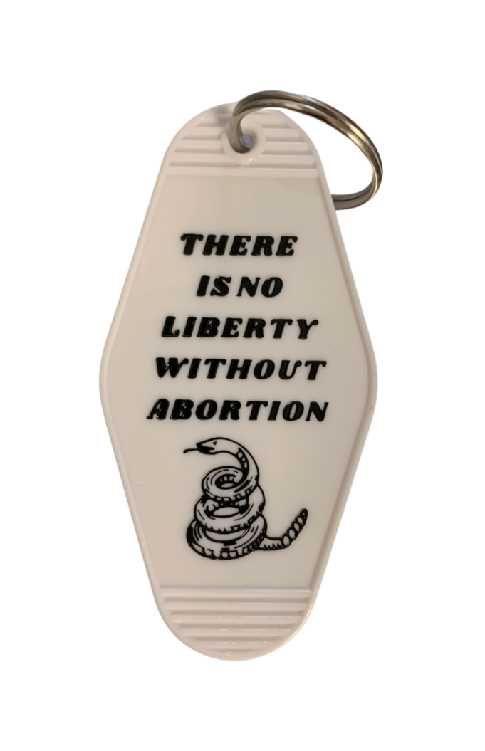 Black and white keychain with the phrase 'There is no liberty without abortion' on a split ring, styled like a classic motel key tag.