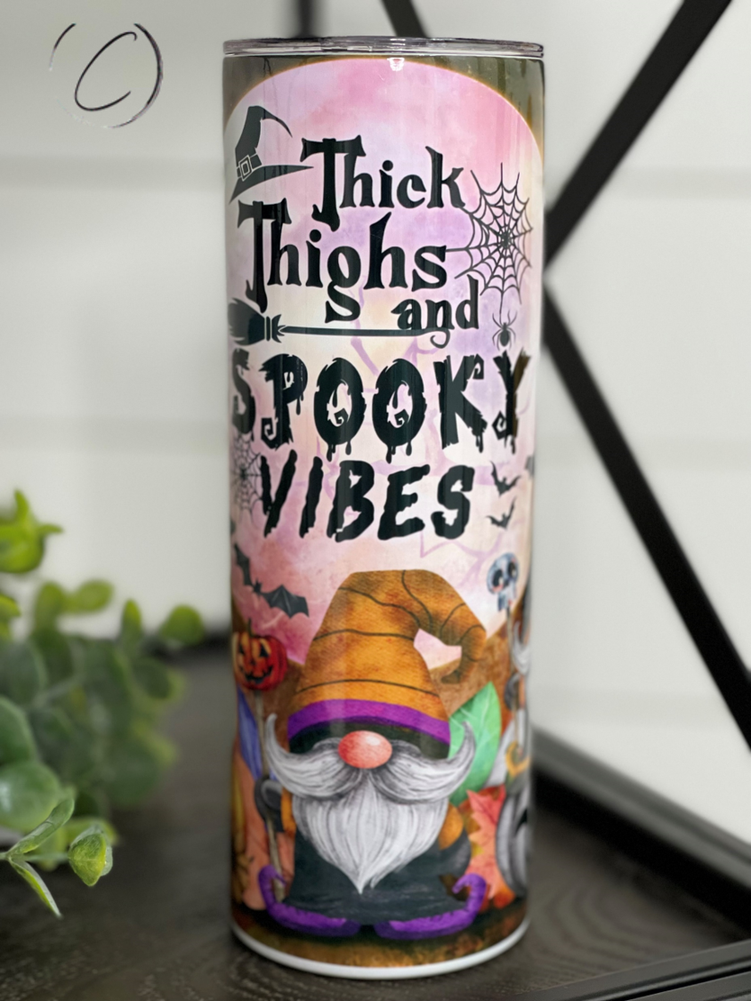 A stylish 20oz skinny tumbler featuring a vibrant design with the phrase 'Thick Thighs & Spooky Vibes', perfect for Halloween and everyday use.