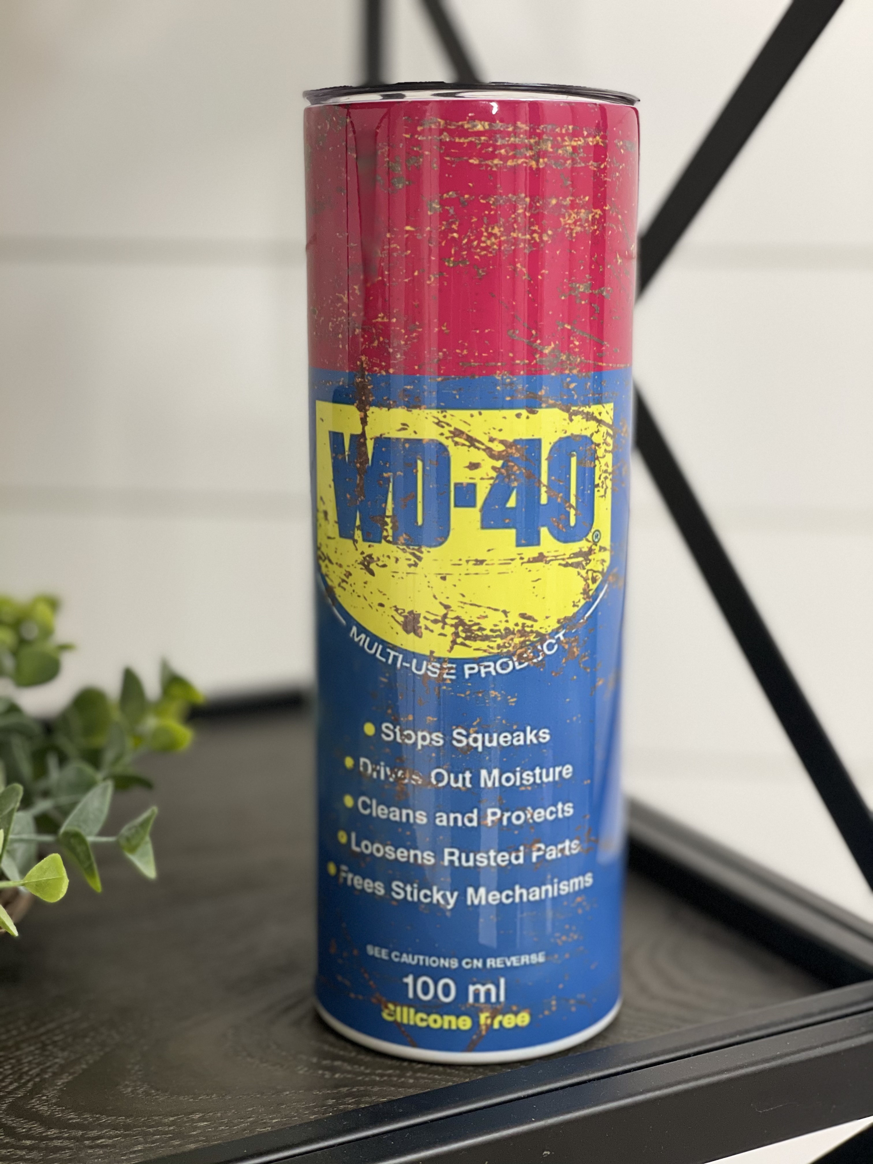 WD-40 20oz Skinny Tumbler with a full wrap design, featuring a reusable straw and insulated for hot and cold beverages.